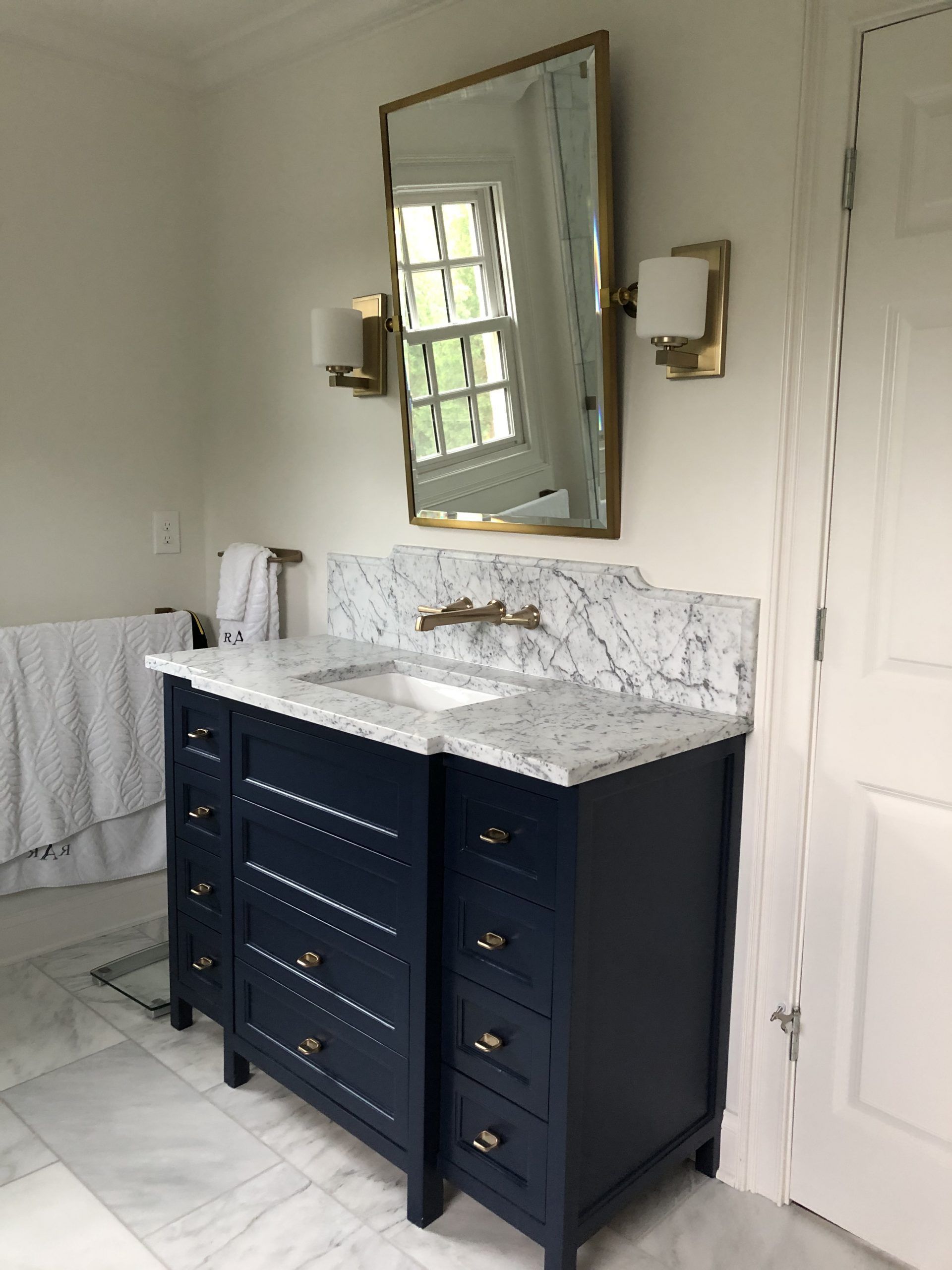 A bathroom with a blue vanity and a mirror