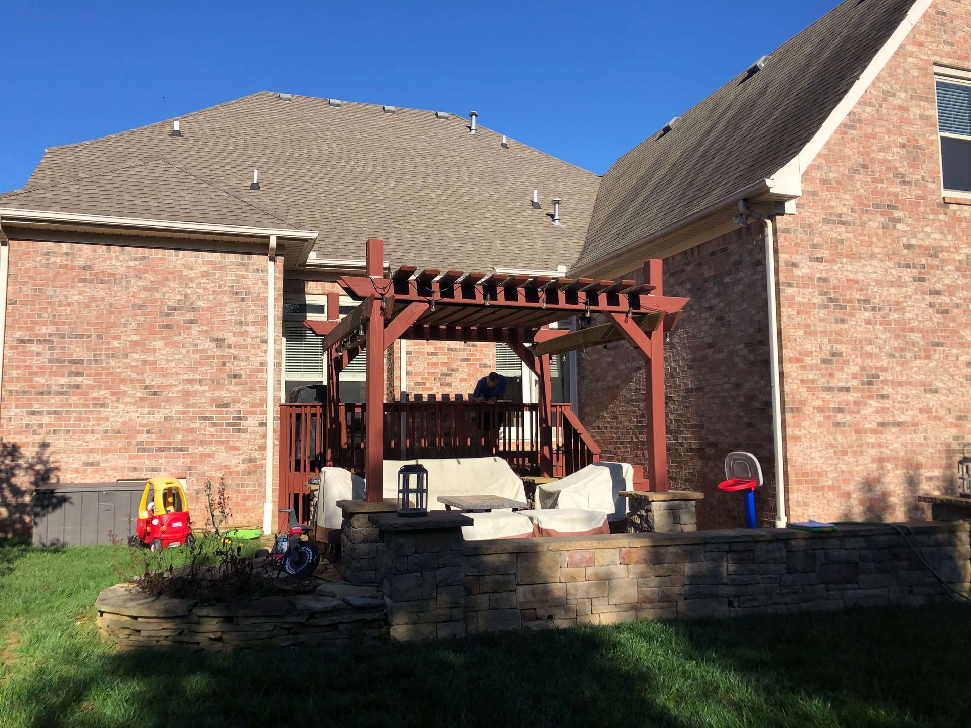 A brick house with a wooden pergola in the backyard.