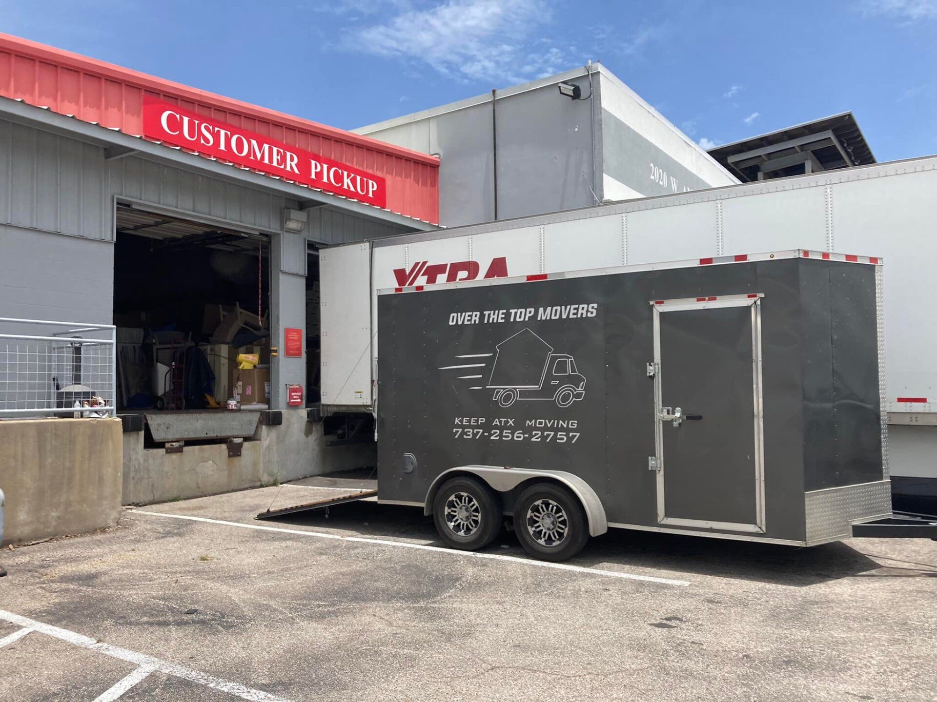 A trailer is parked in front of a warehouse.