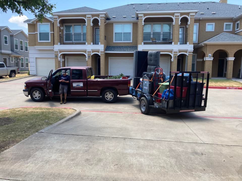 A red truck is parked in front of a house with a trailer attached to it