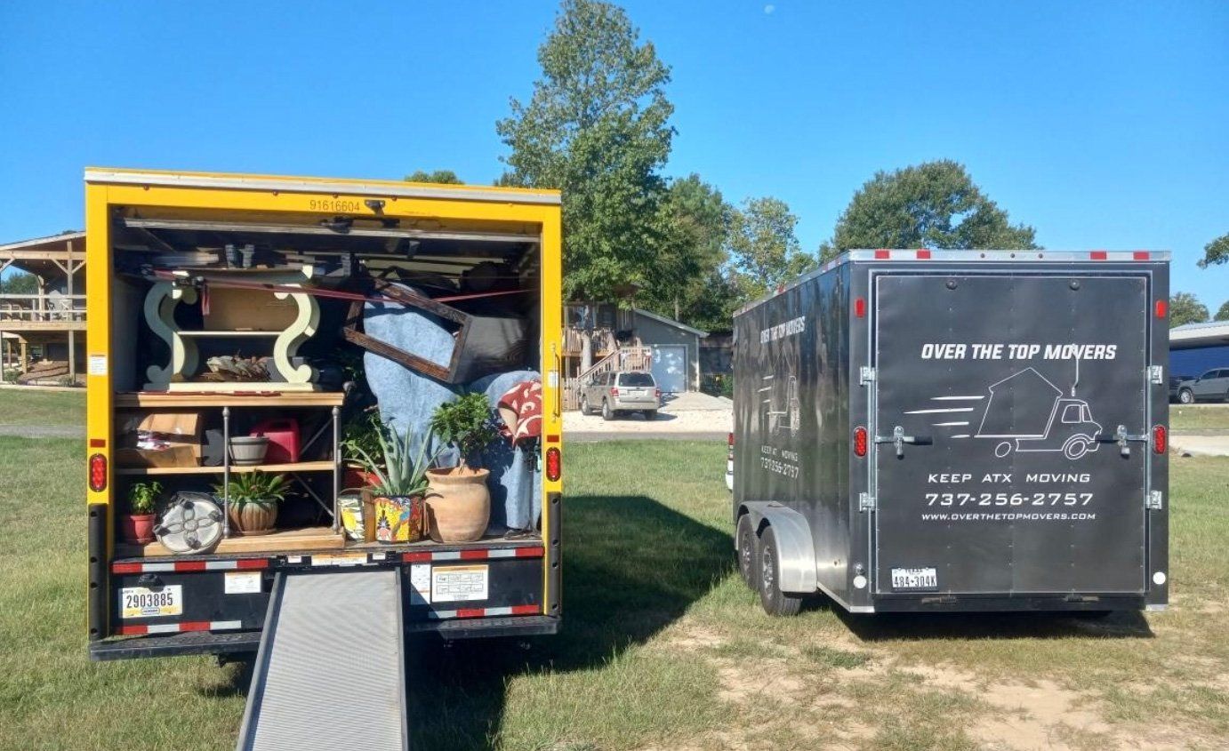 A yellow truck and a black trailer are parked next to each other in a grassy field.