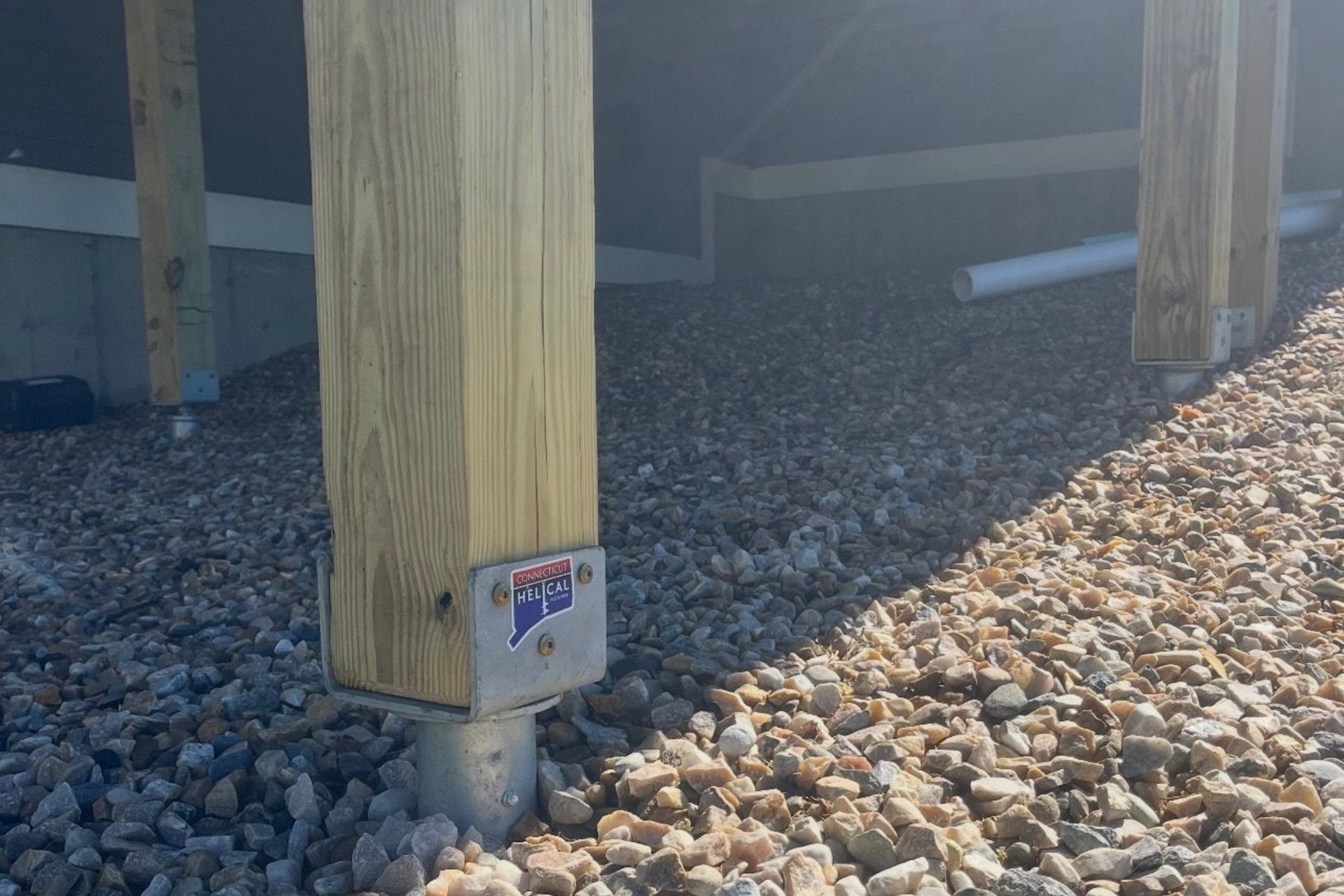 Deck supported by metal posts on a grassy hillside.