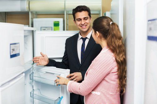 un uomo che mostra un frigorifero a una donna