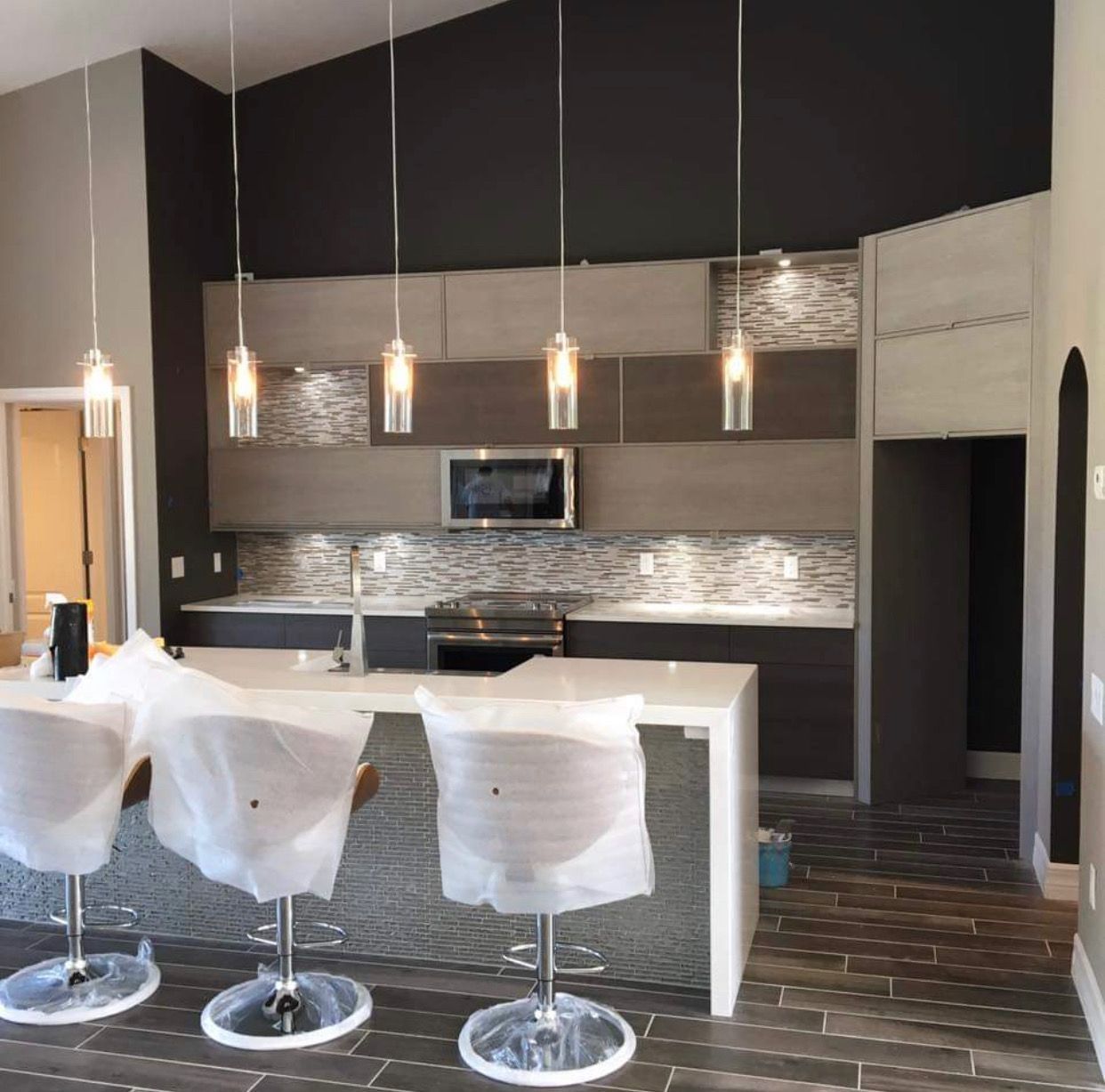 Modern kitchen with overhead pendant lights, island seating, and gray cabinetry.