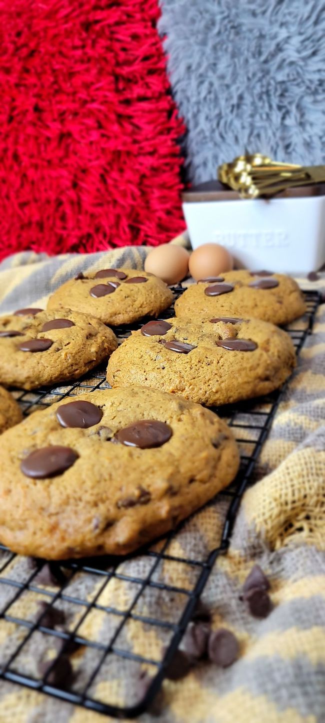 A bunch of chocolate chip cookies sitting on top of a cooling rack.