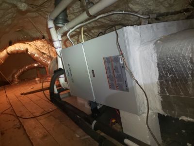 A Bosch HVAC air handler unit installed in a floored attic space with attached ductwork and pipes.