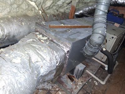 An HVAC air handler unit with connected flexible ductwork situated in an attic space with spray foam insulation.