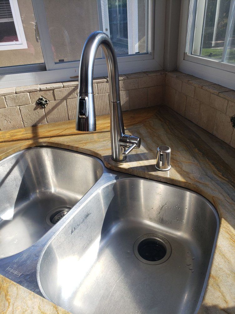 A stainless steel kitchen sink with a faucet on a counter.