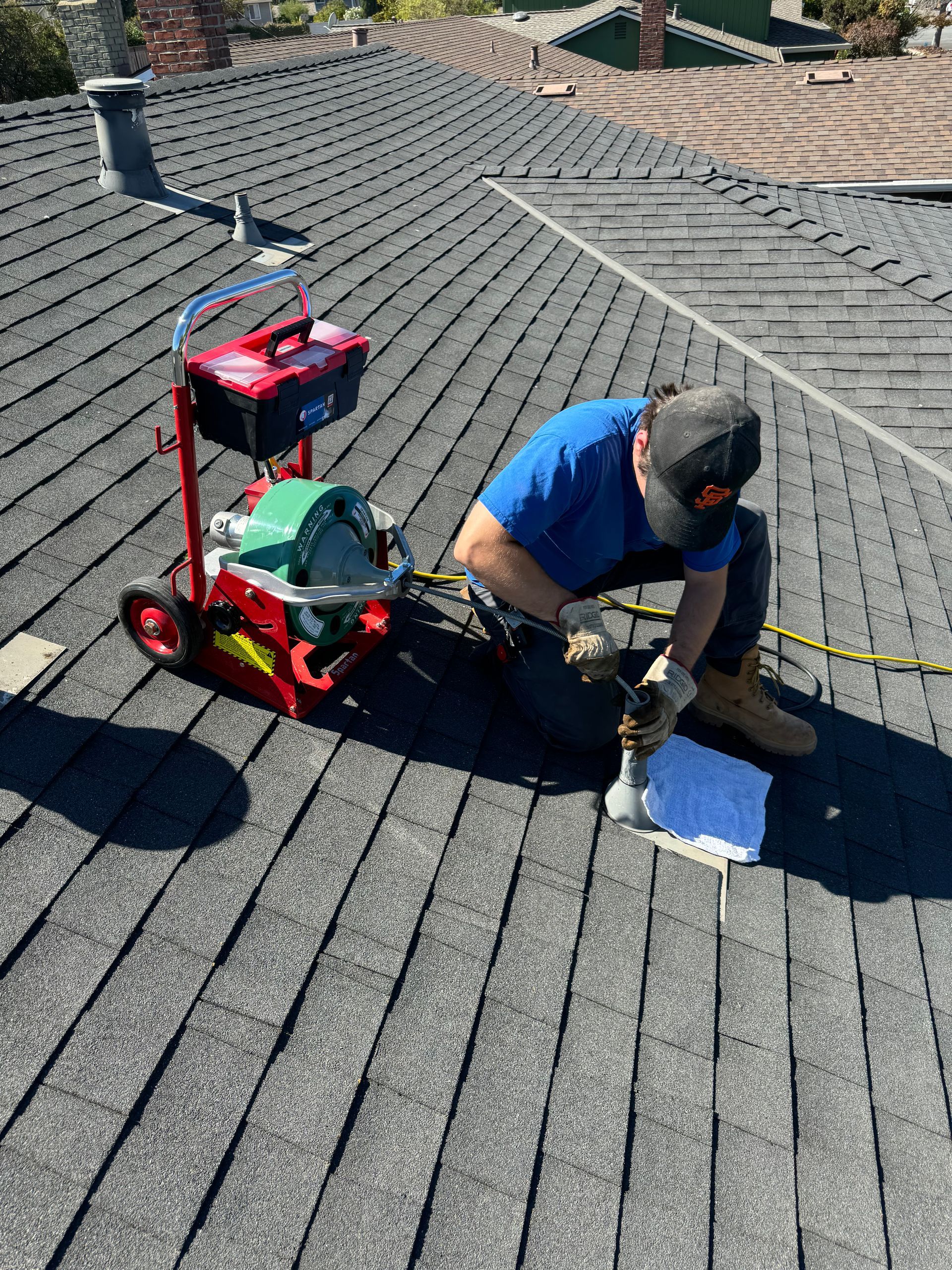A man is kneeling on top of a roof with a tool.