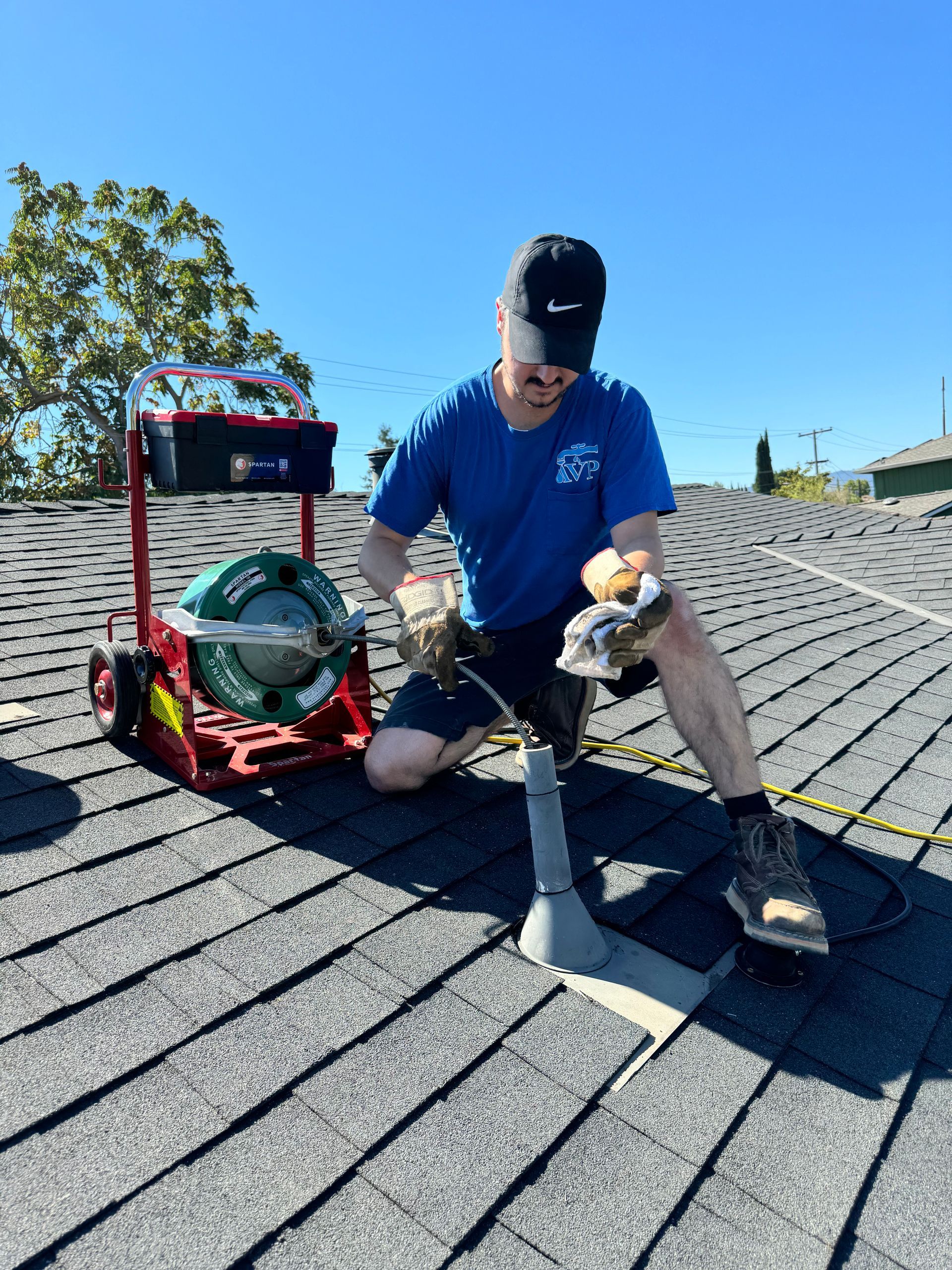 A man is kneeling on a roof with a tool.