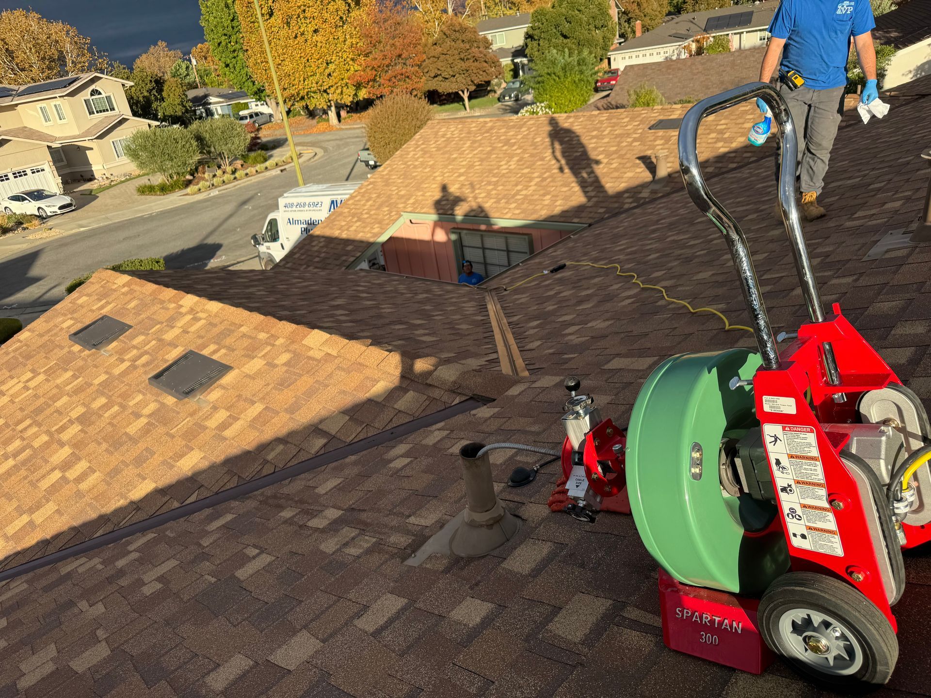 A man is standing on top of a roof next to a machine.