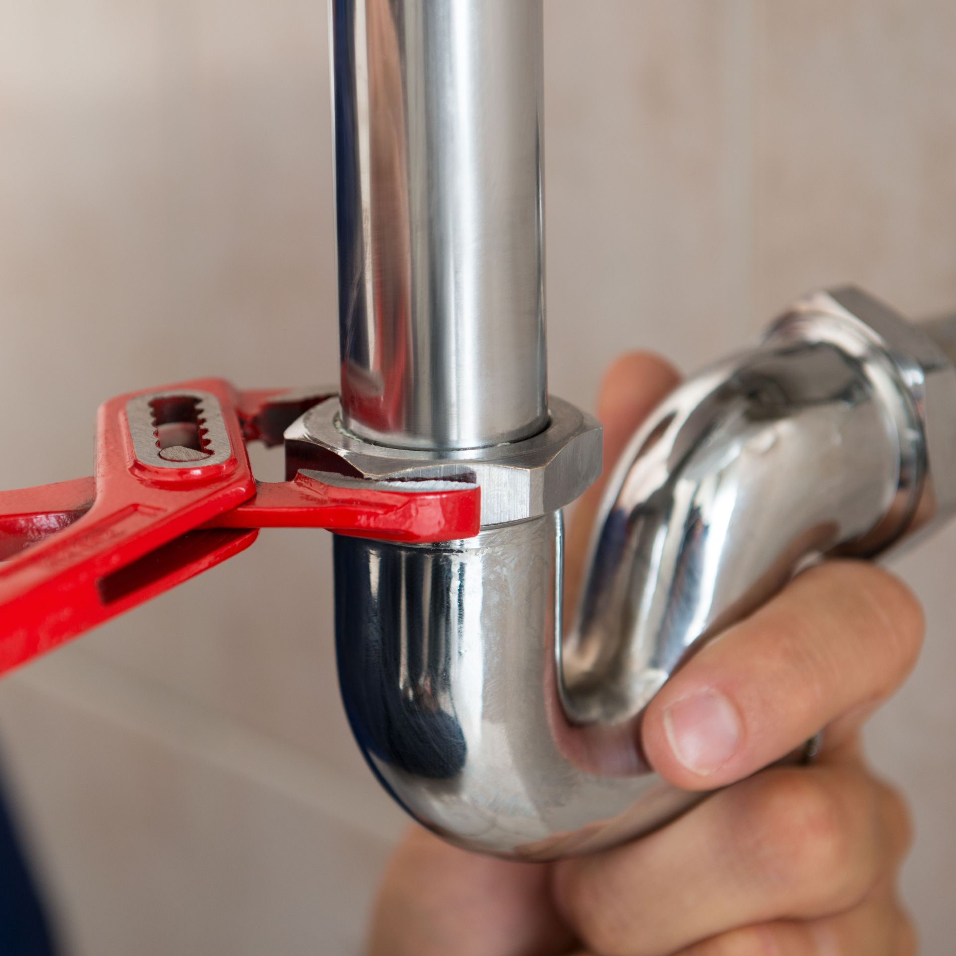 A person is fixing a pipe with a wrench.