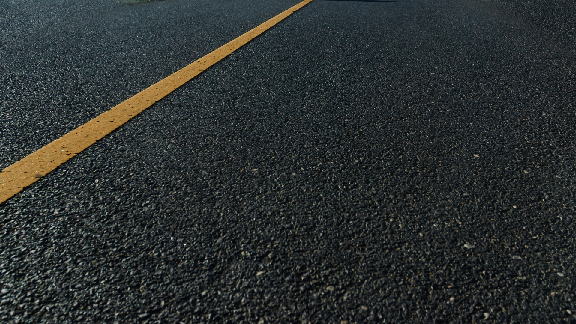 A close up of a road with a yellow line on it.
