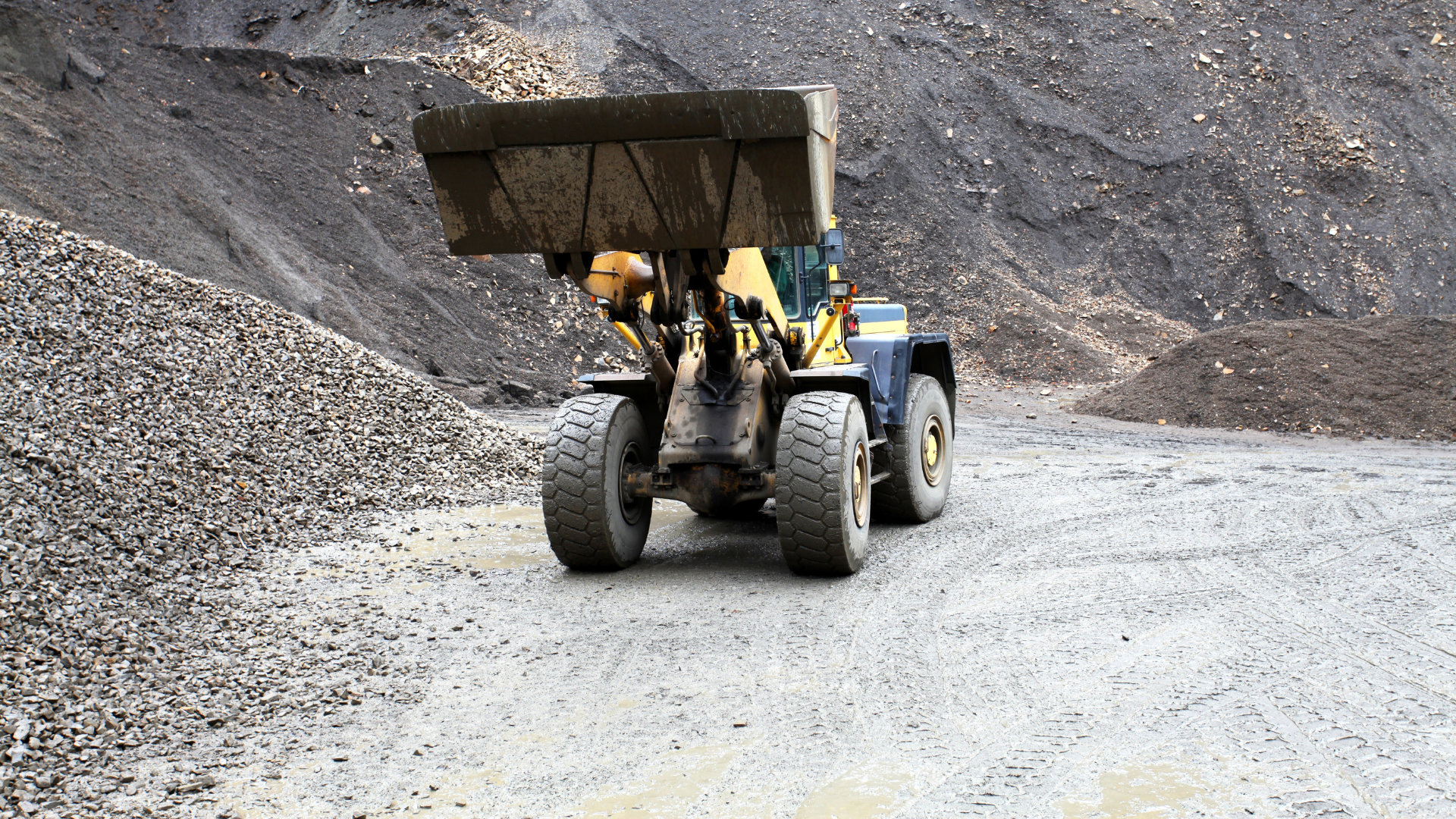 A yellow bulldozer is driving down a dirt road.