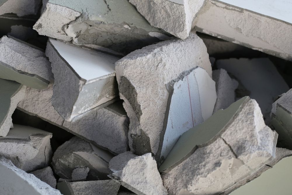 Pile of broken tiles with white and gray surfaces.