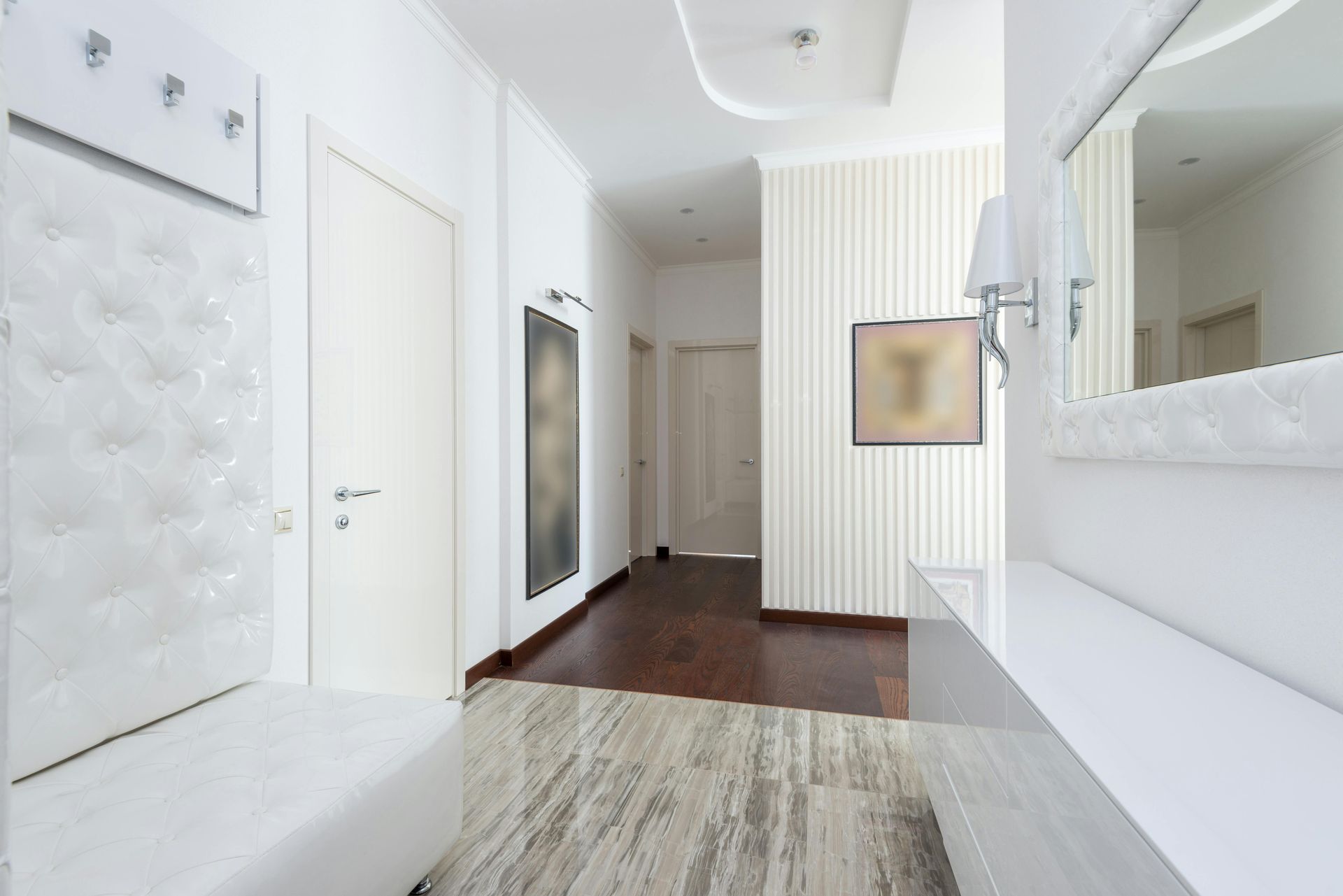 White hallway with bench, door, art, and mirror; dark wood floor, modern decor.