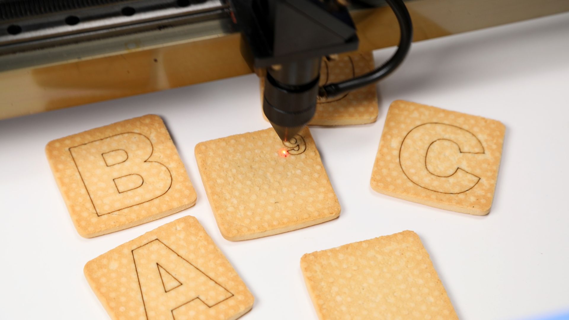 A machine is cutting out letters on some cookies