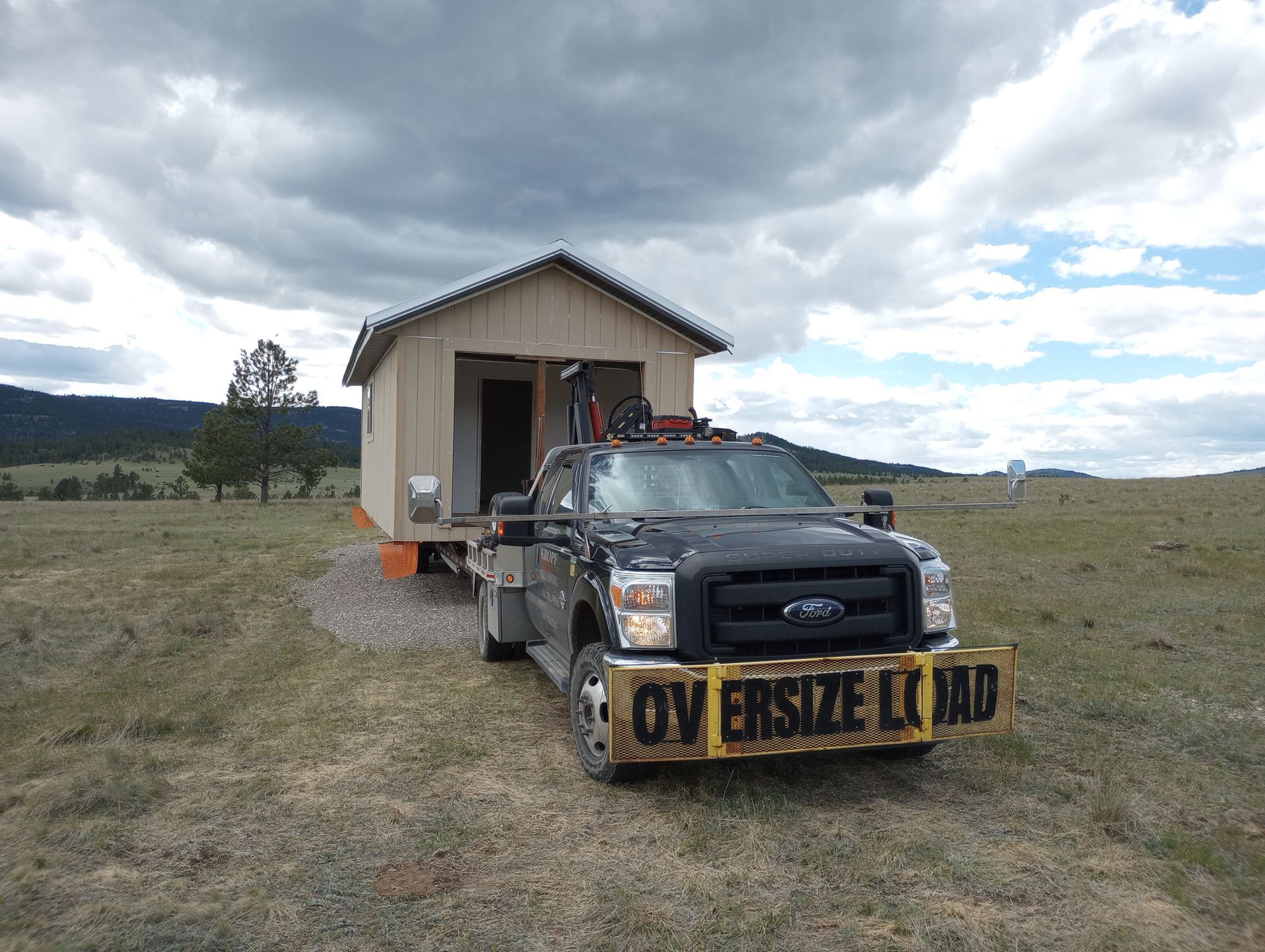A ford truck is carrying a small house on a trailer