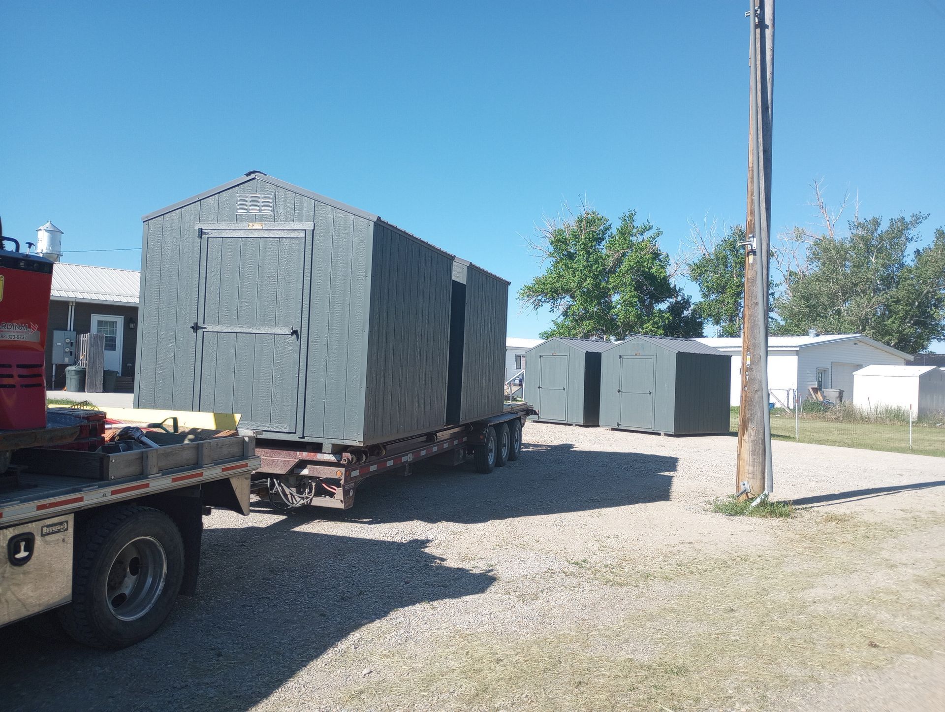 A truck is carrying a trailer with a shed on it.