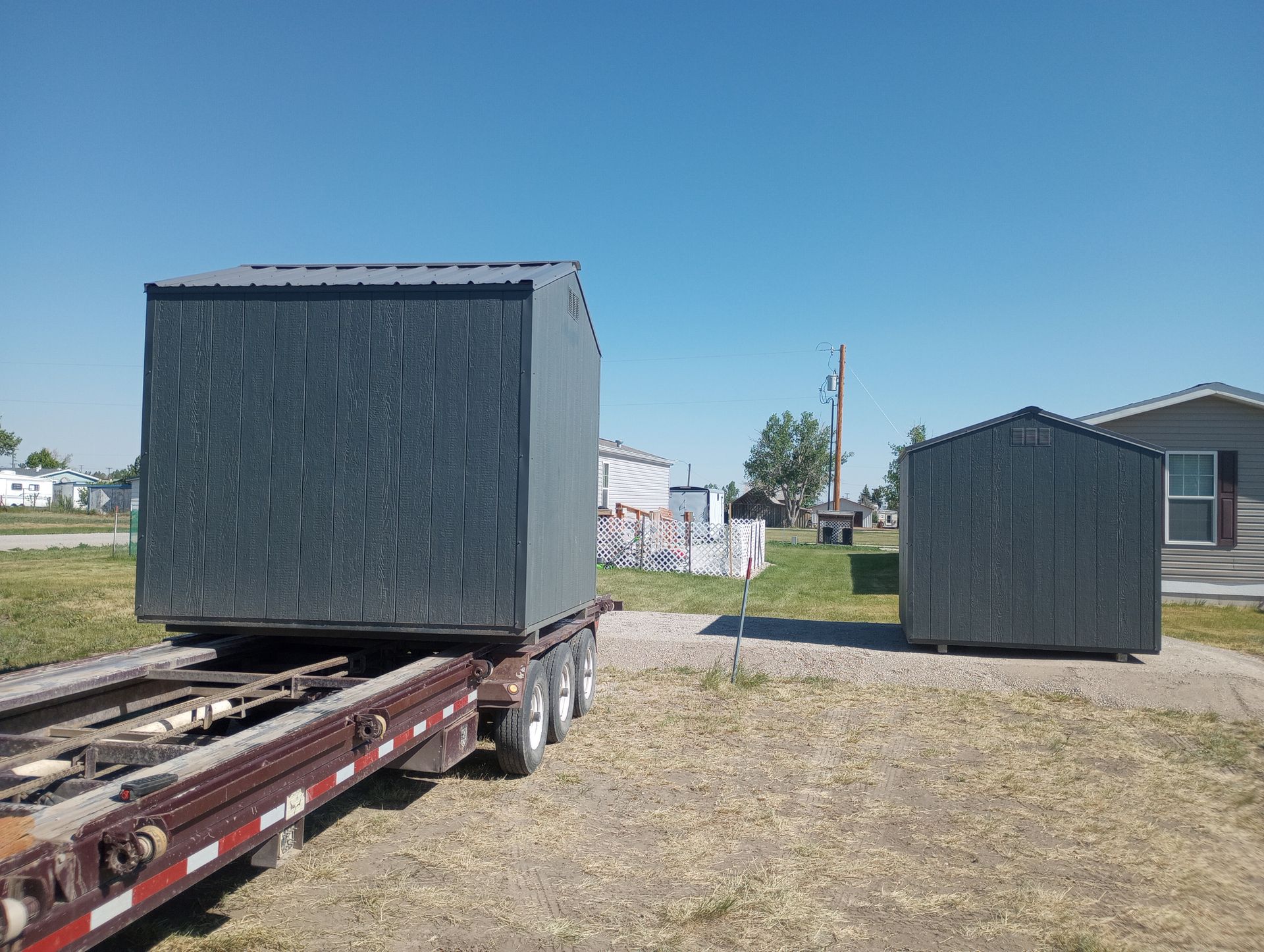 Two sheds are being transported on a trailer.