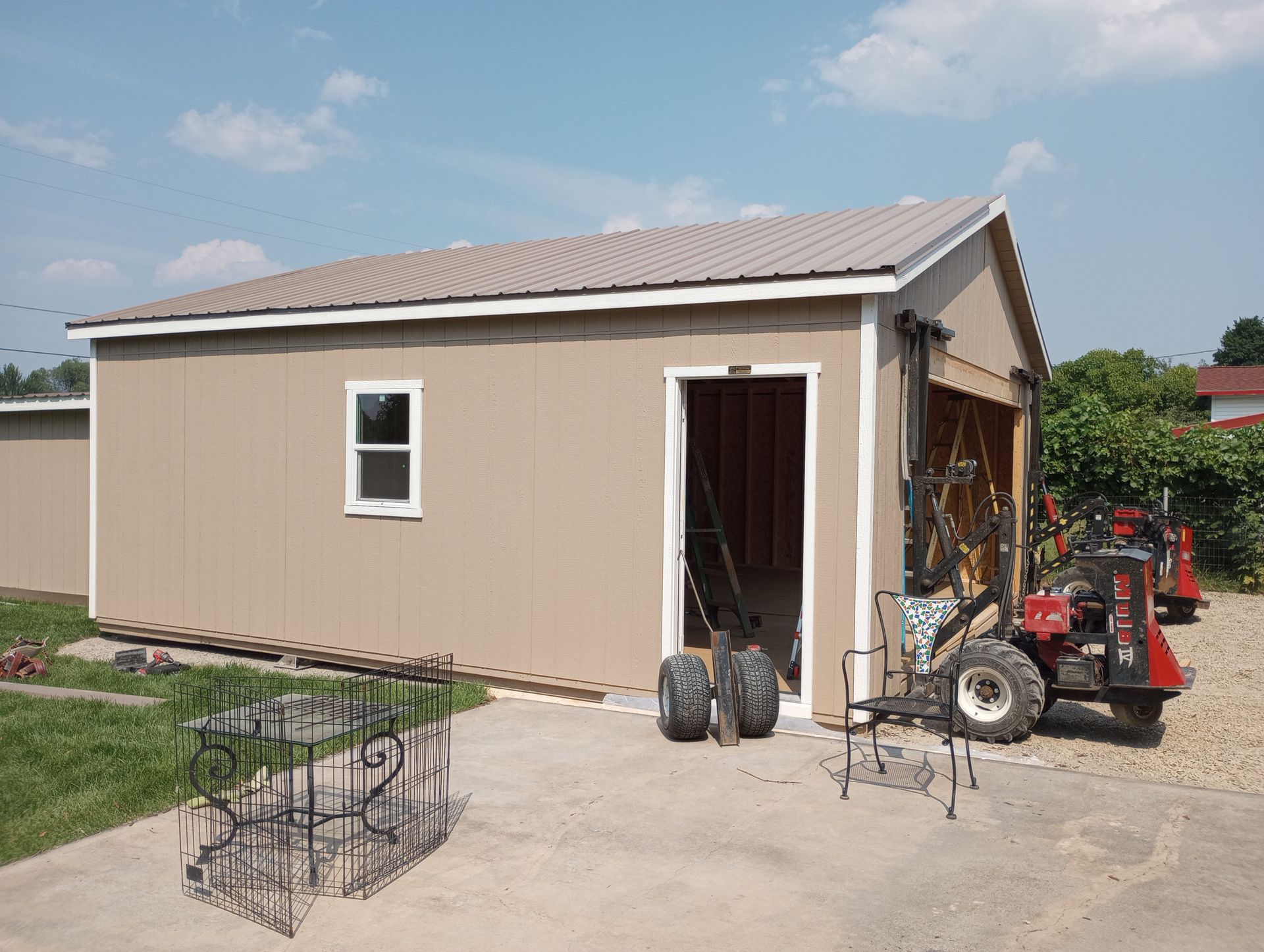 A small garage with a tractor parked in front of it