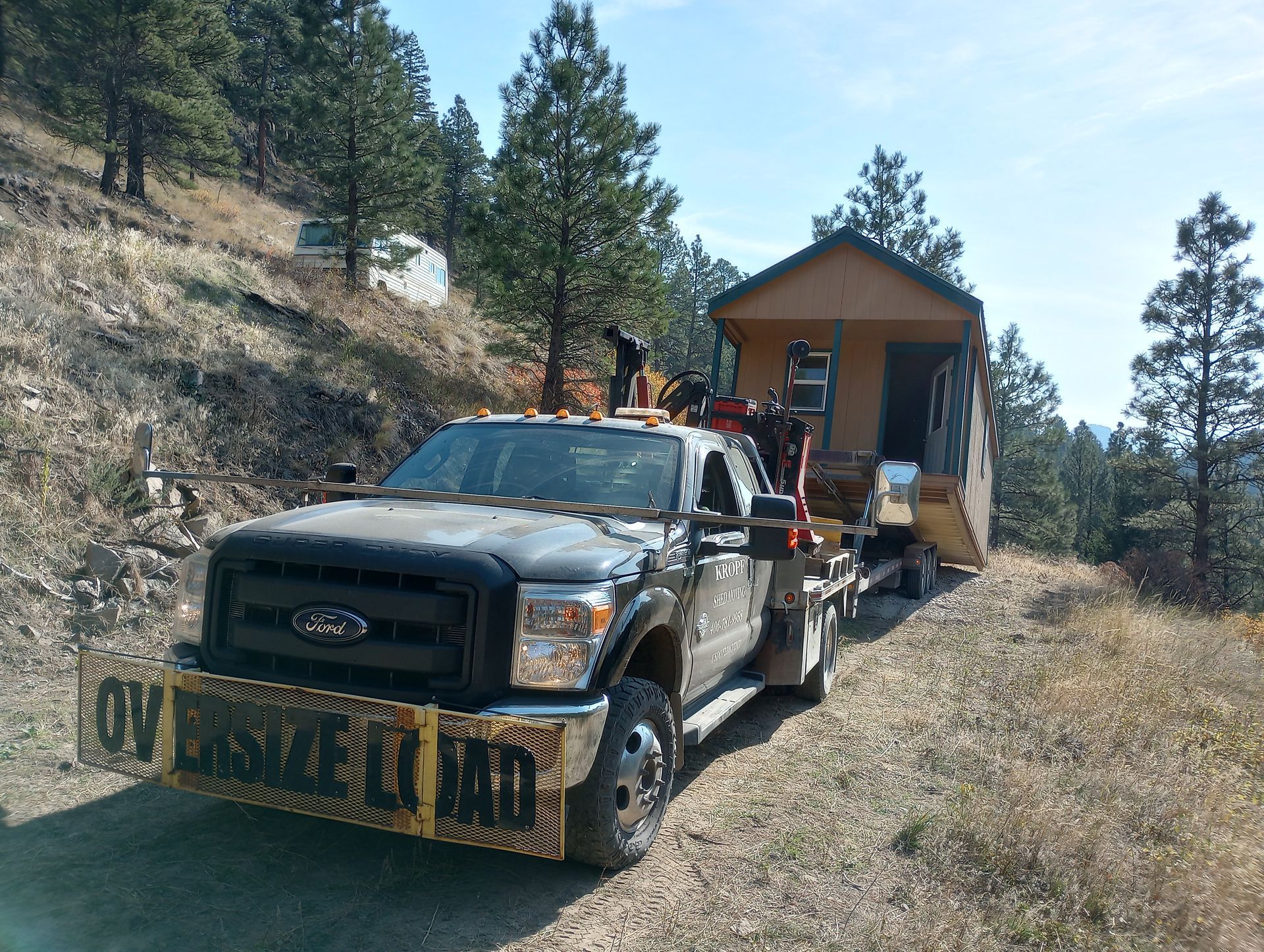 A truck is towing a small house on a dirt road.