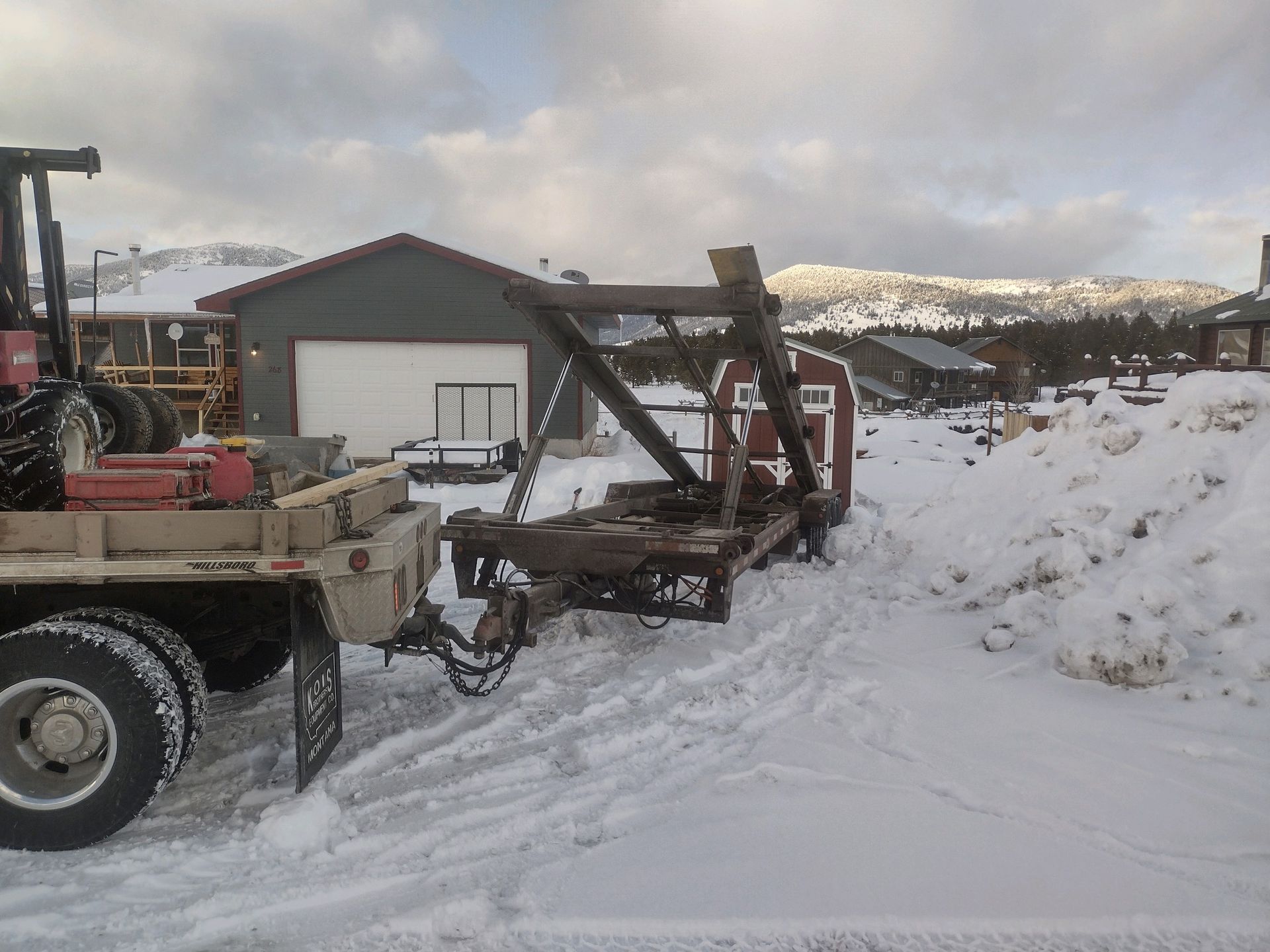 A truck with a trailer attached to it is parked in the snow.