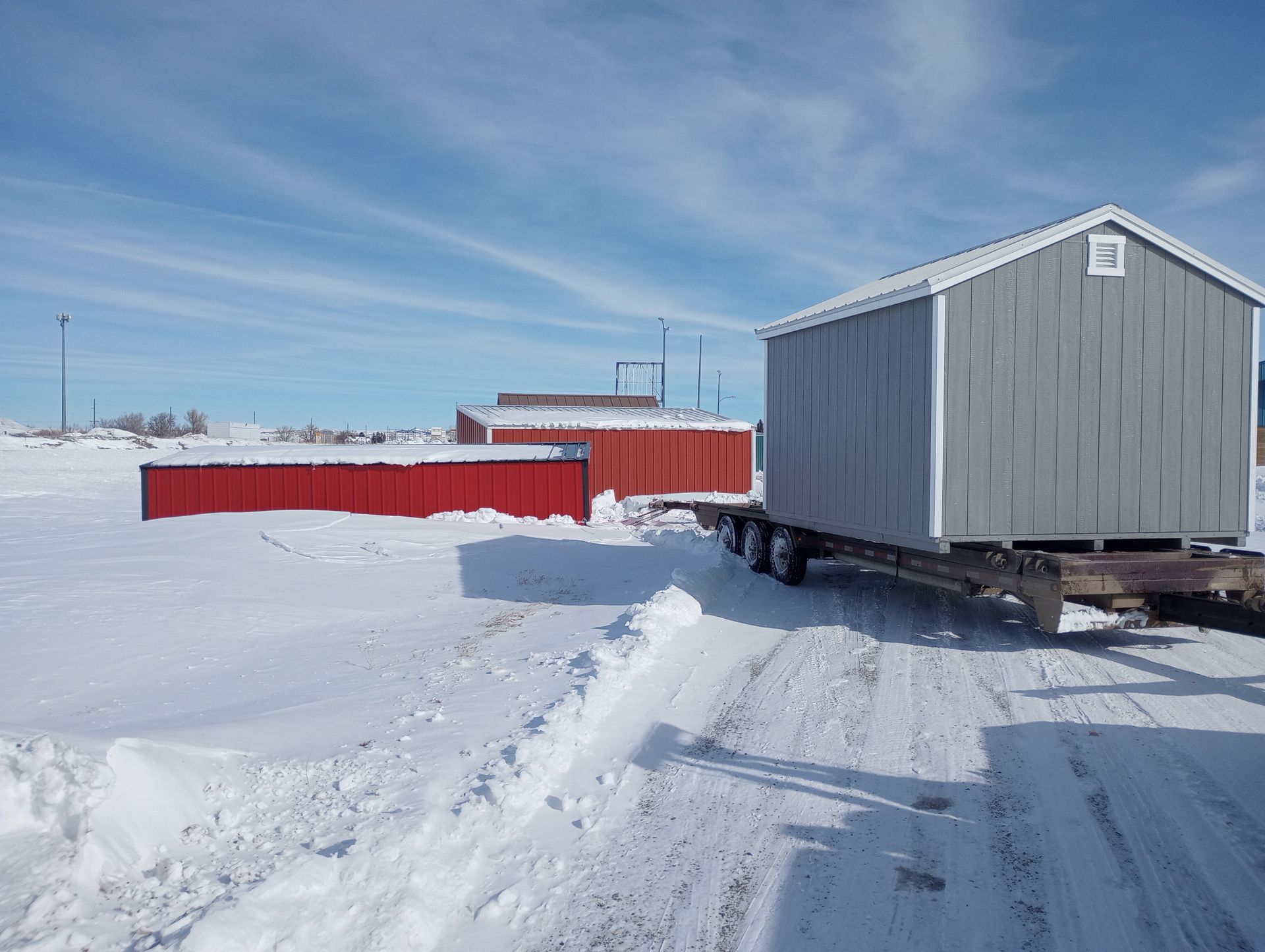 A trailer is carrying a shed on a snowy road