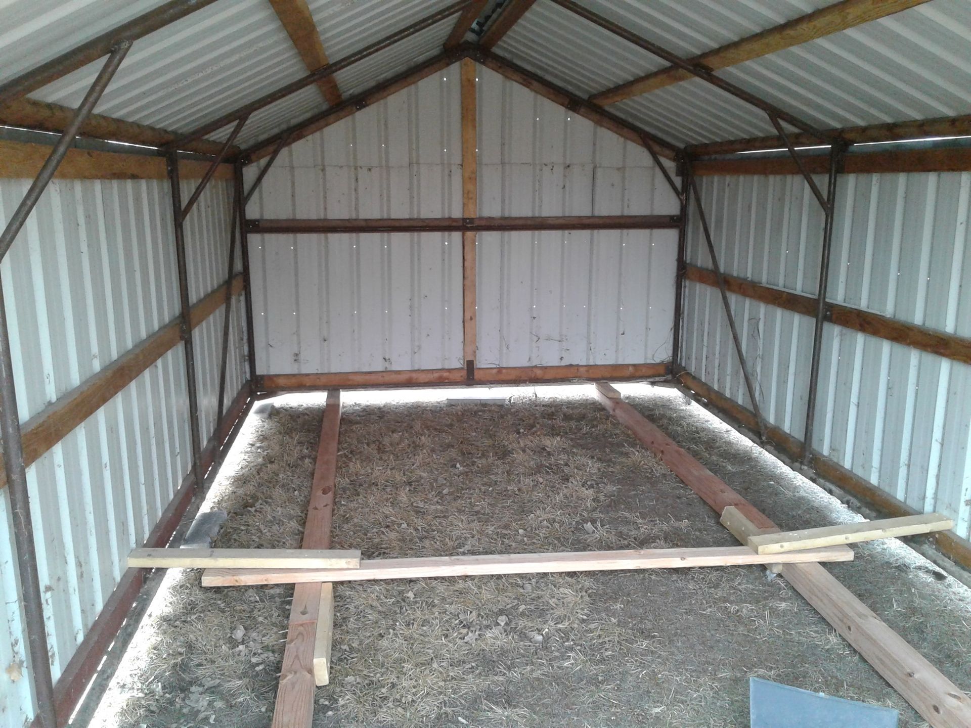 A shed with a wooden floor and a metal roof