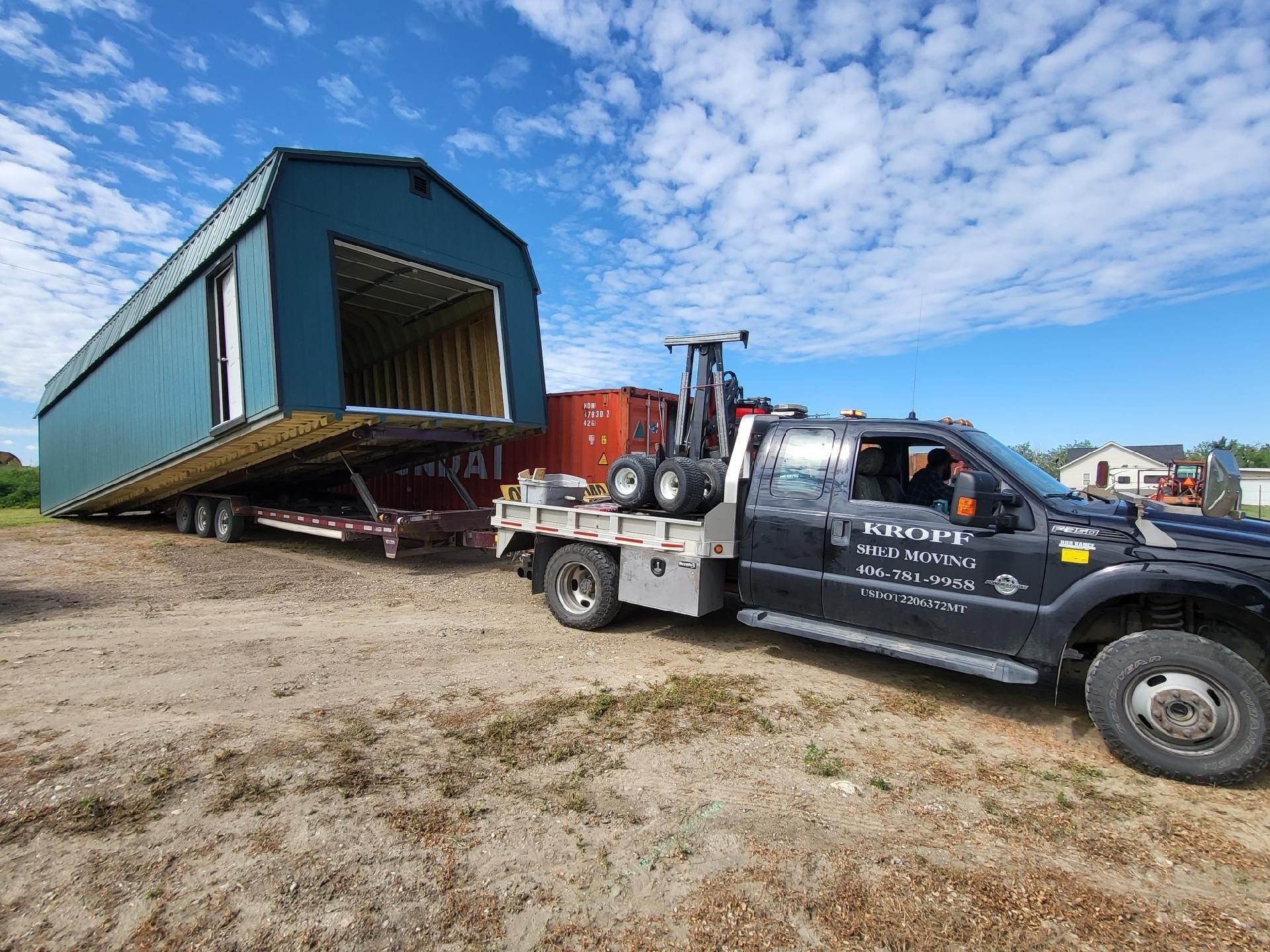 A tow truck is towing a large building on a trailer.
