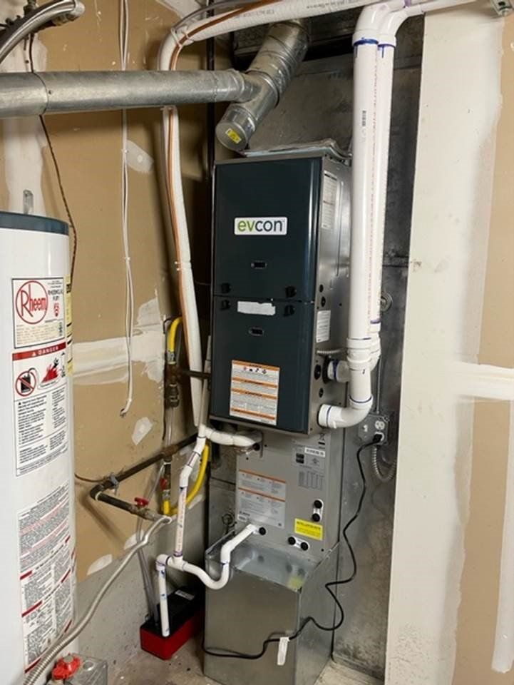 A furnace is sitting in a basement next to a water heater.
