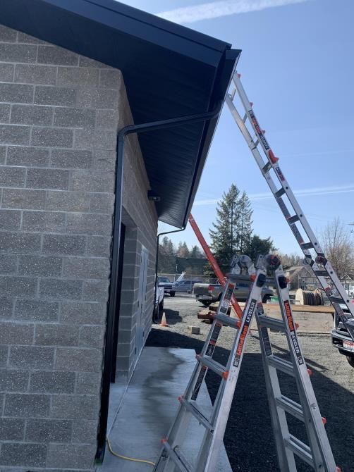 An individual wearing gloves and holding a cloth is cleaning gutters after repairs.