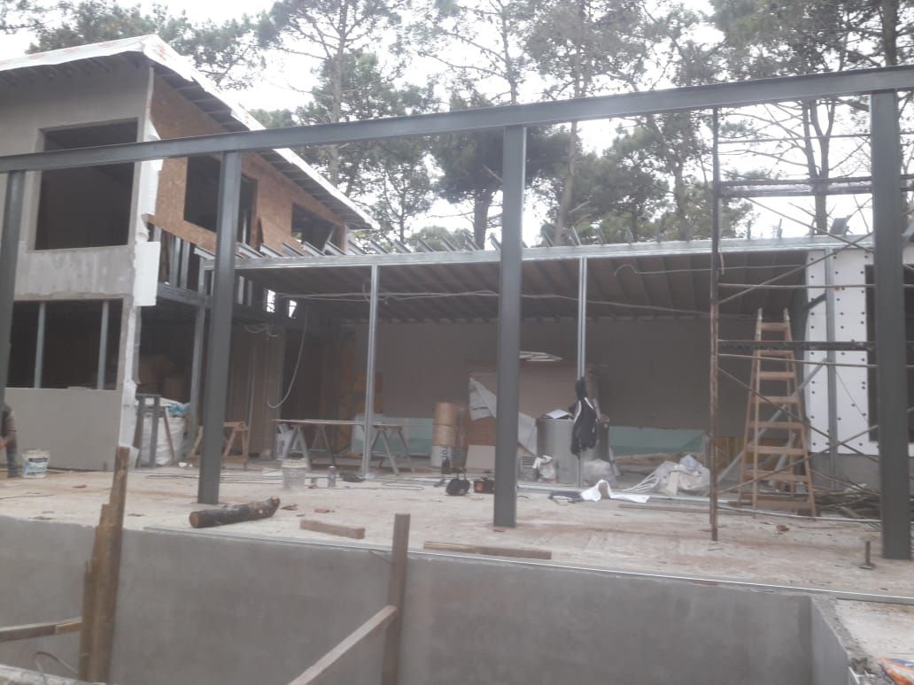 Sitio de construcción: estructura de acero, parcialmente construida, árboles al fondo.