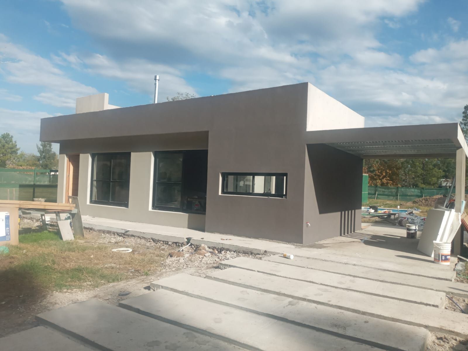 Casa moderna, gris, con cochera bajo un cielo nublado.