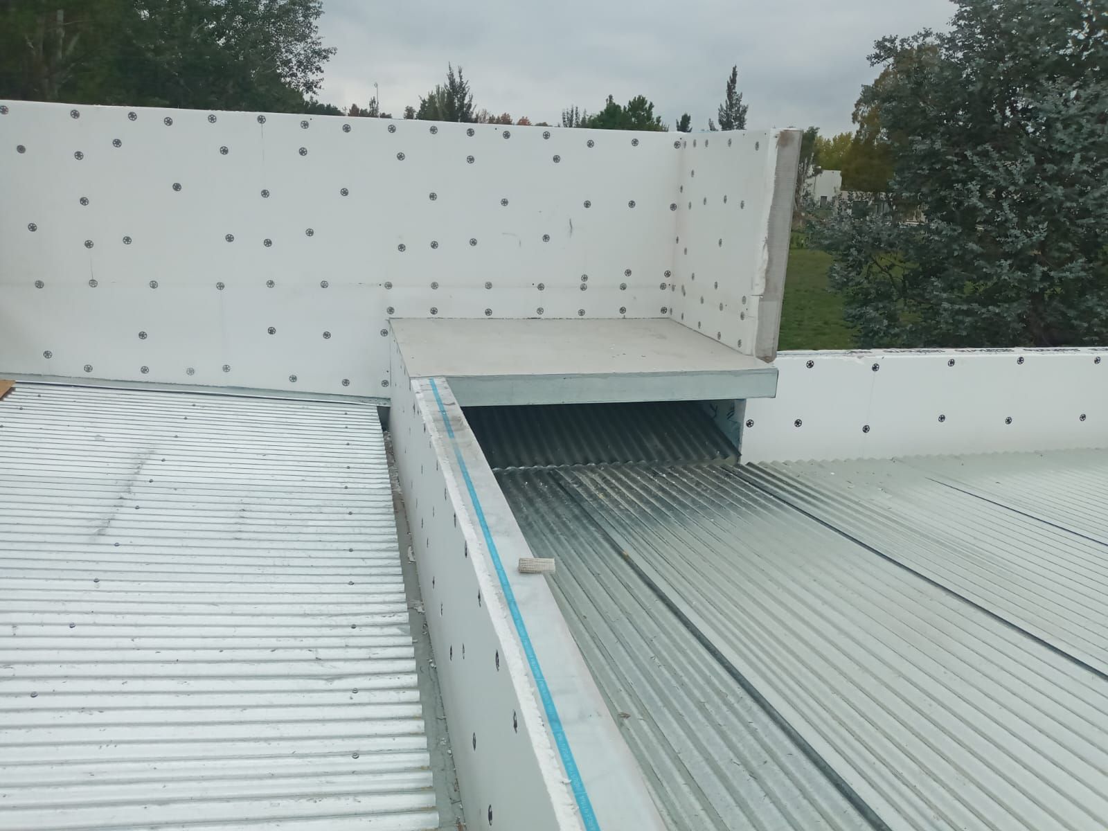 Techo de metal corrugado blanco con paredes aisladas blancas; exterior.