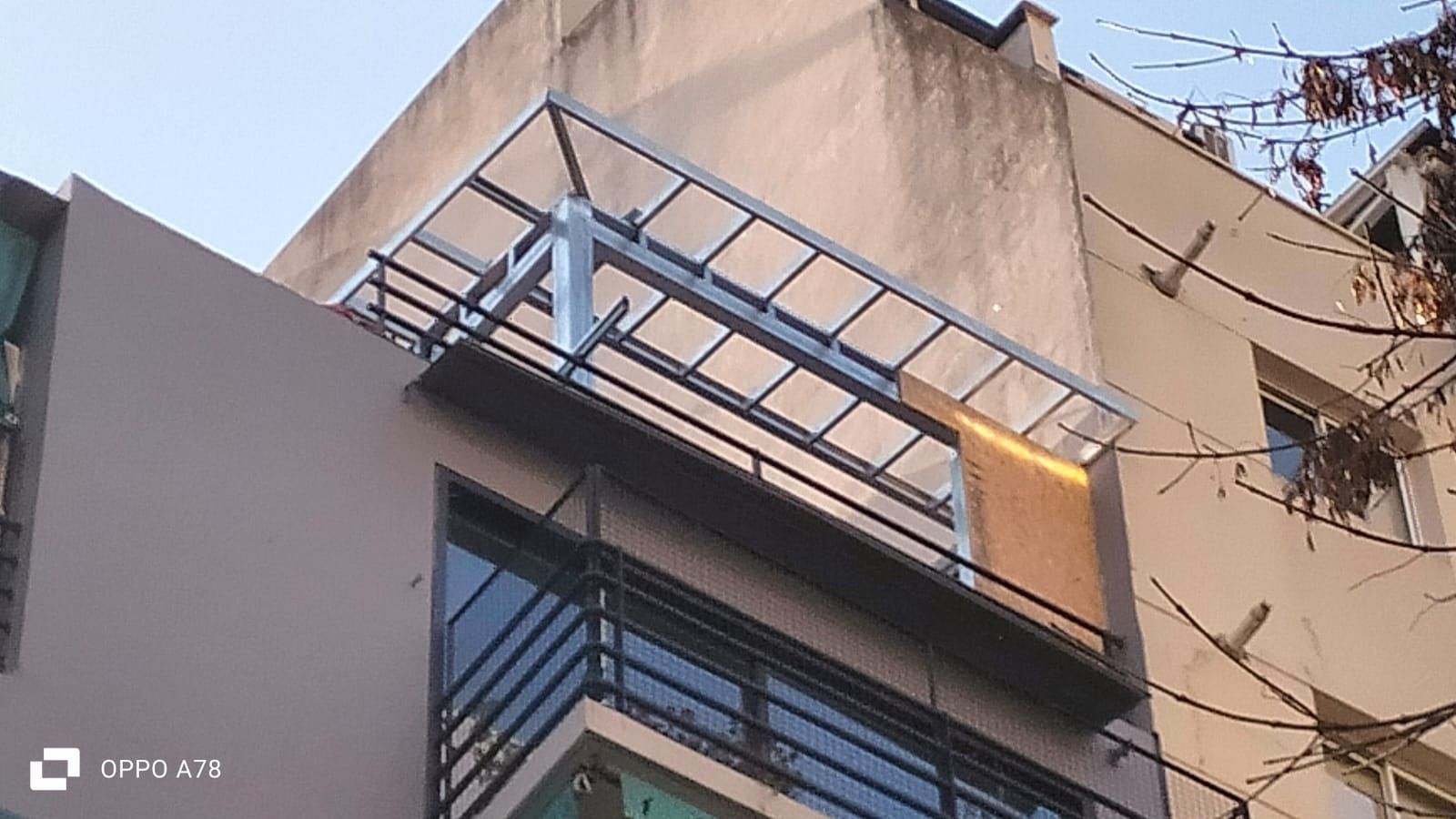 Exterior del edificio con balcón y barandilla metálica, cubierto por cubierta translúcida.