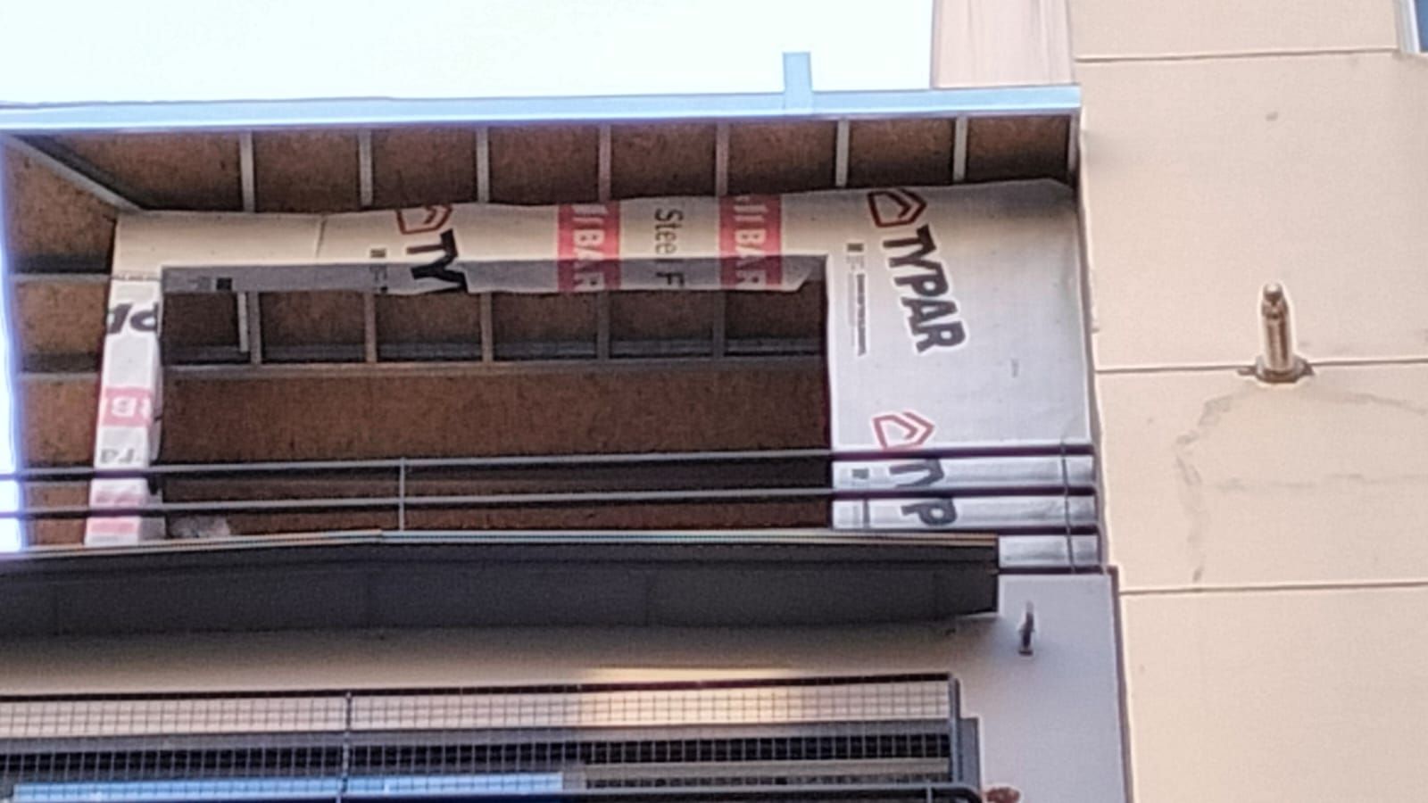 Pared exterior con construcción expuesta, envoltura Typar visible, estructura de metal.