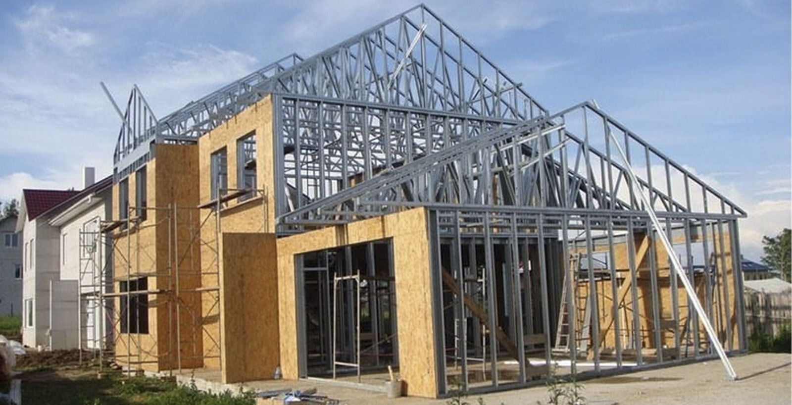 Casa en construcción con estructura de acero y paneles de madera en un día soleado.