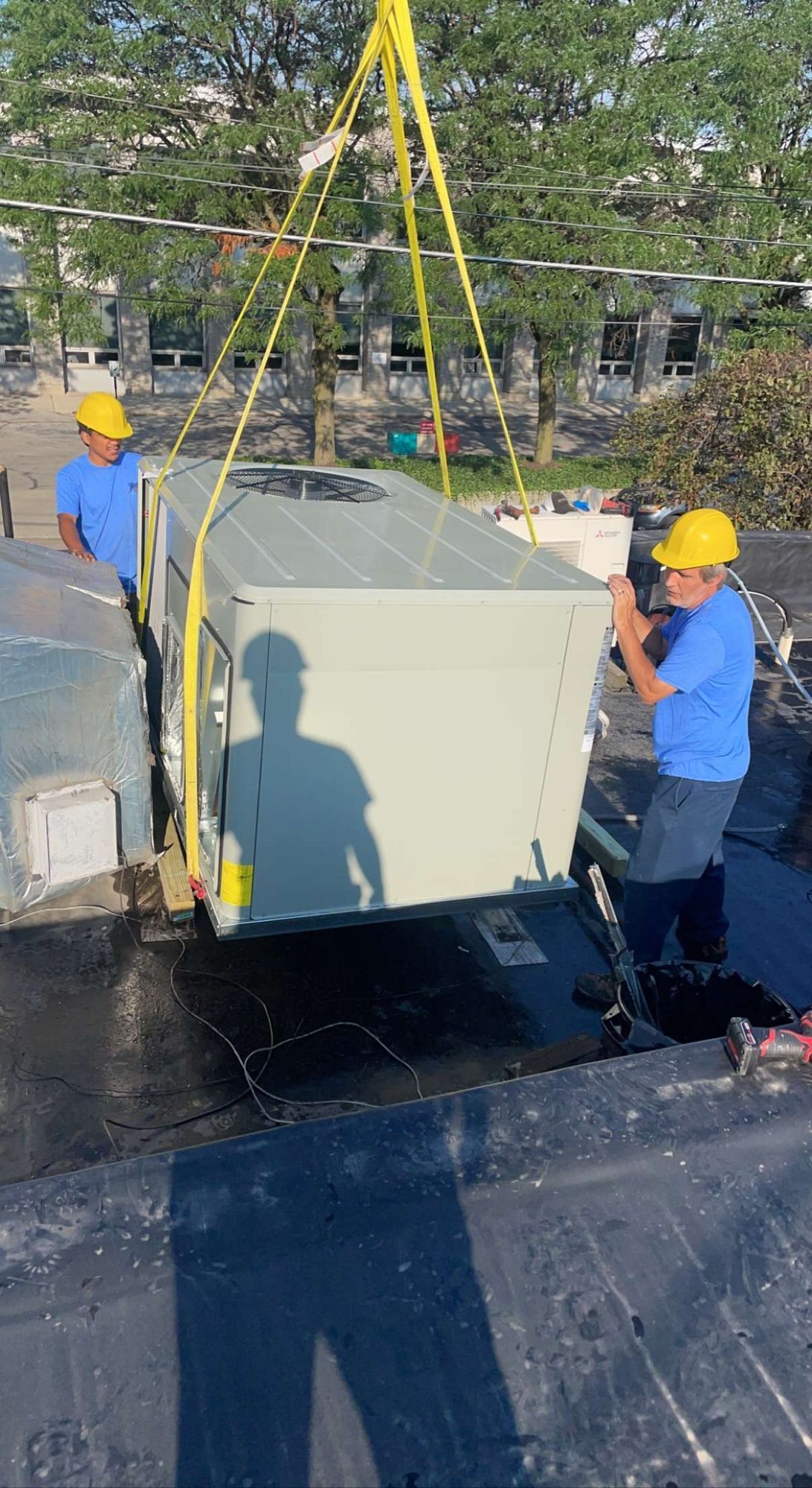 Two men are lifting a large box on top of a roof.
