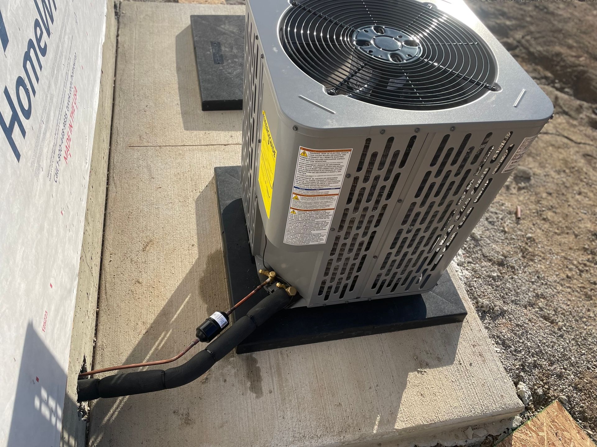 An air conditioner is sitting on a concrete platform next to a wall.