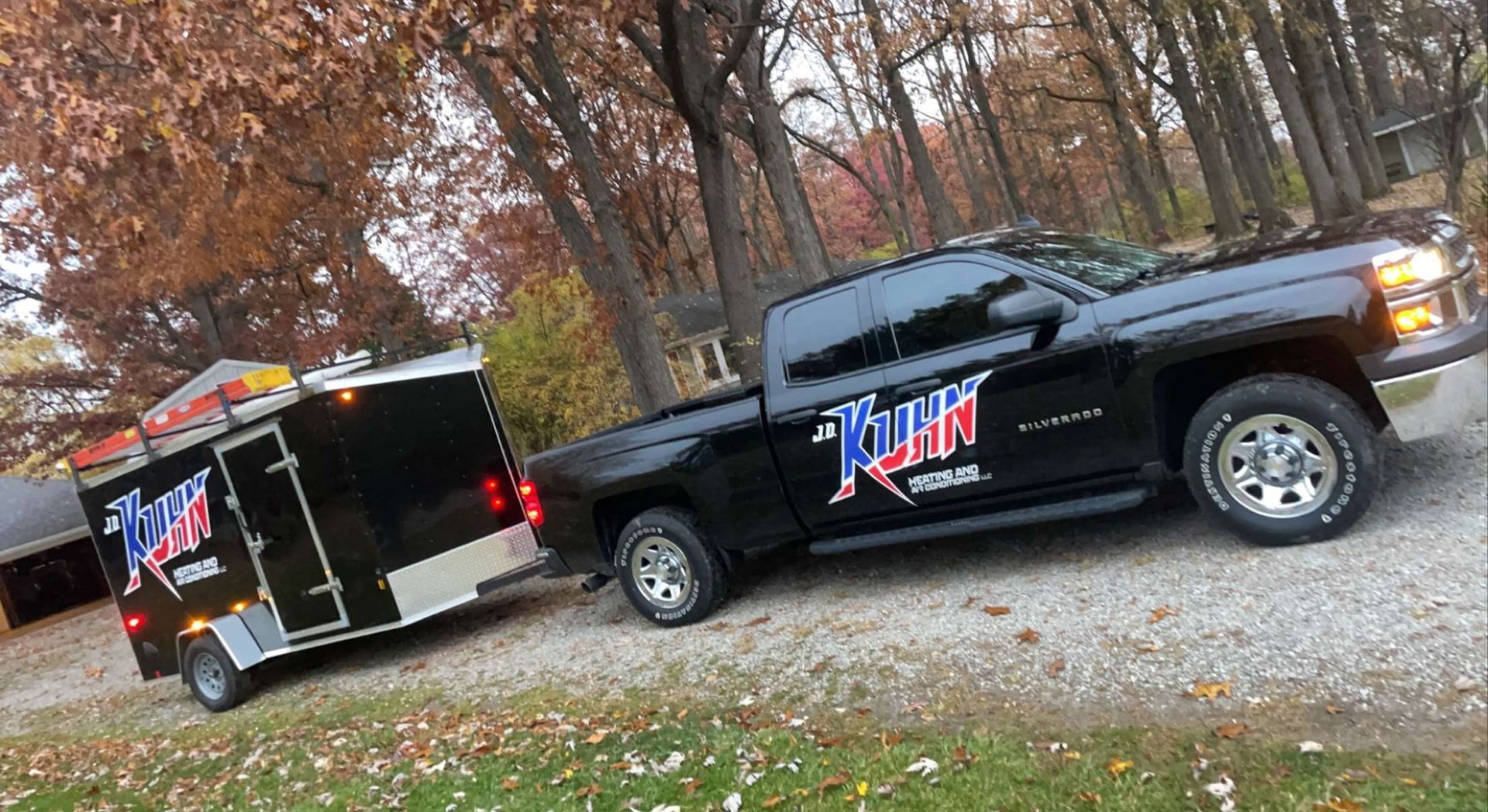 A black truck with a trailer attached to it is parked on a gravel road.