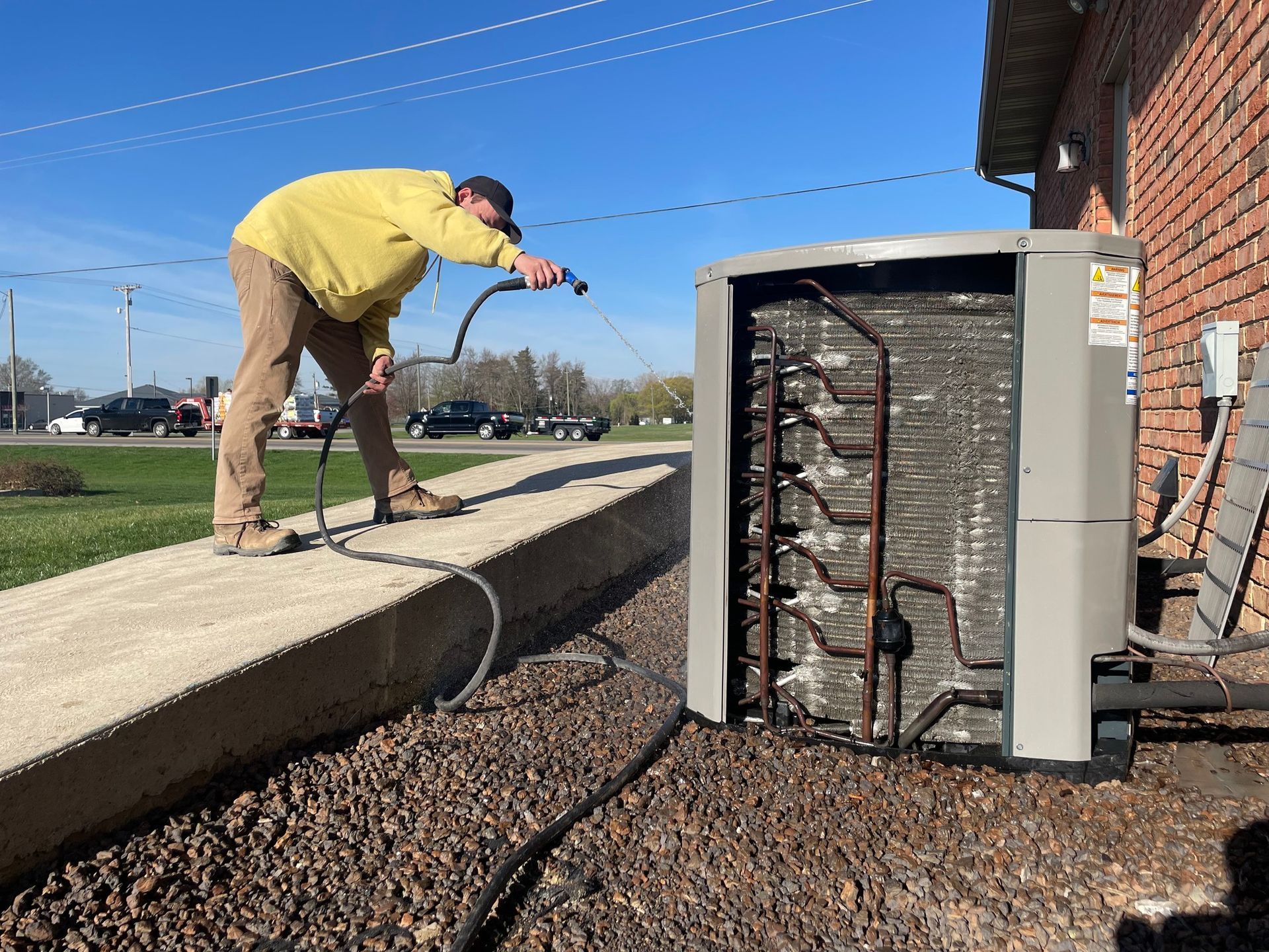A man is working on an air conditioner outside of a building.