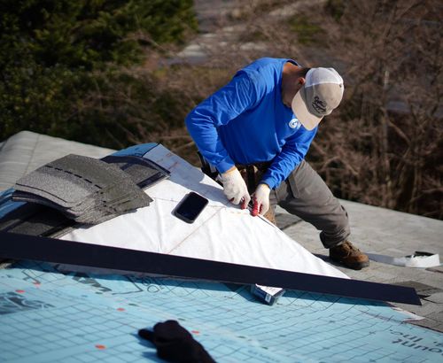 A man in a blue shirt installing shingles on a roof