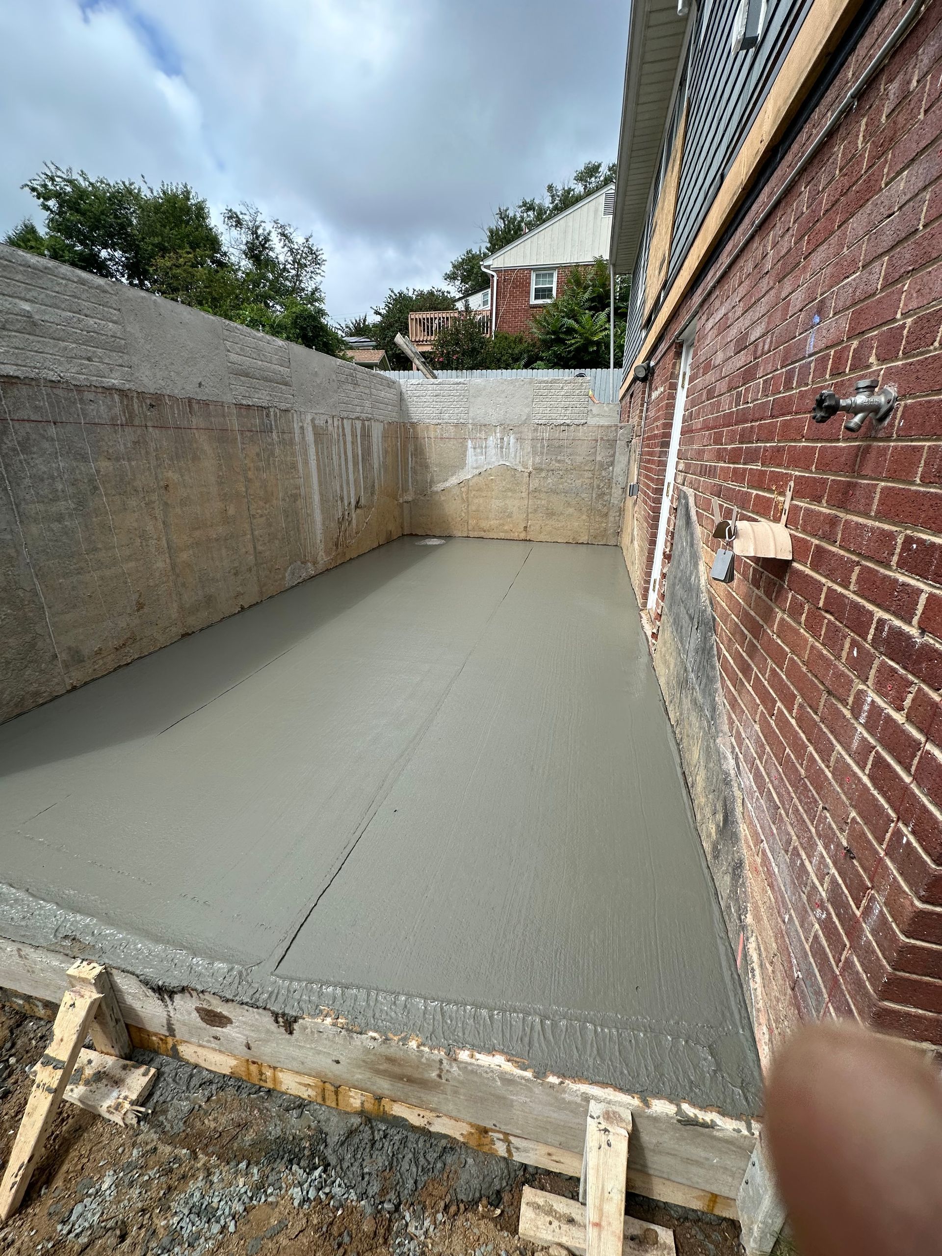 A brick wall with a concrete floor in front of it.