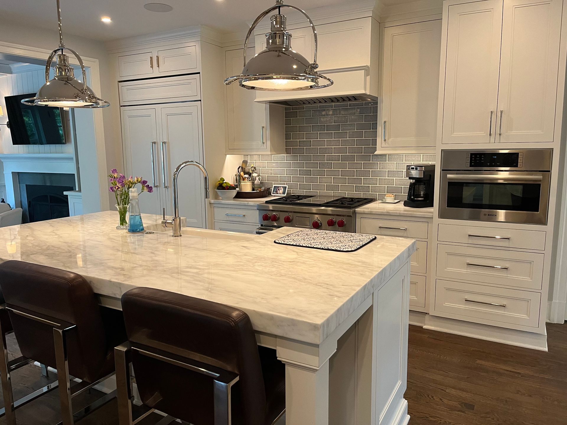 A kitchen with white cabinets , stainless steel appliances, thick counter, farm sink, high end fixtures and a large island.
