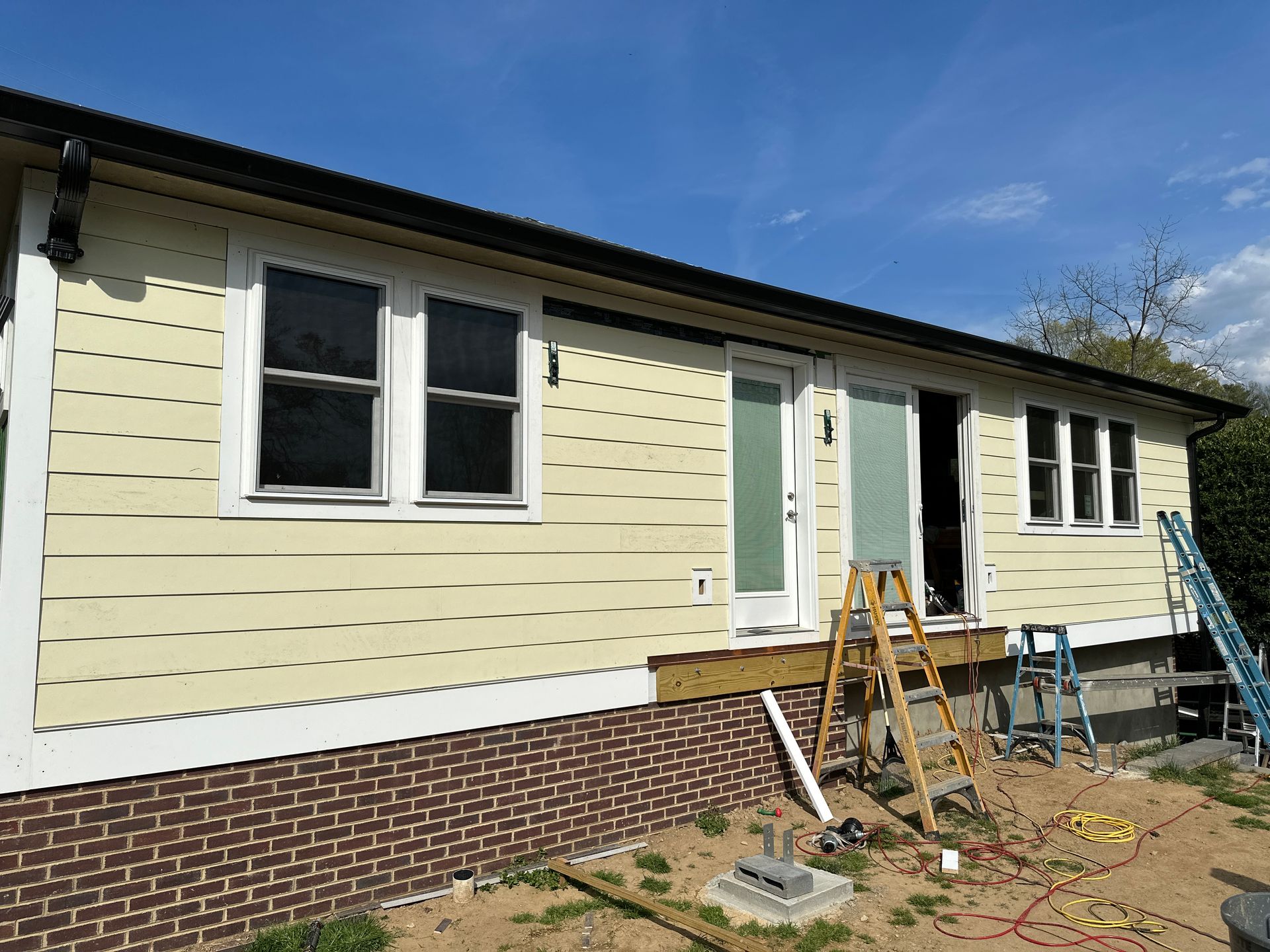 A house is having a deck added with a ladder in front of it.