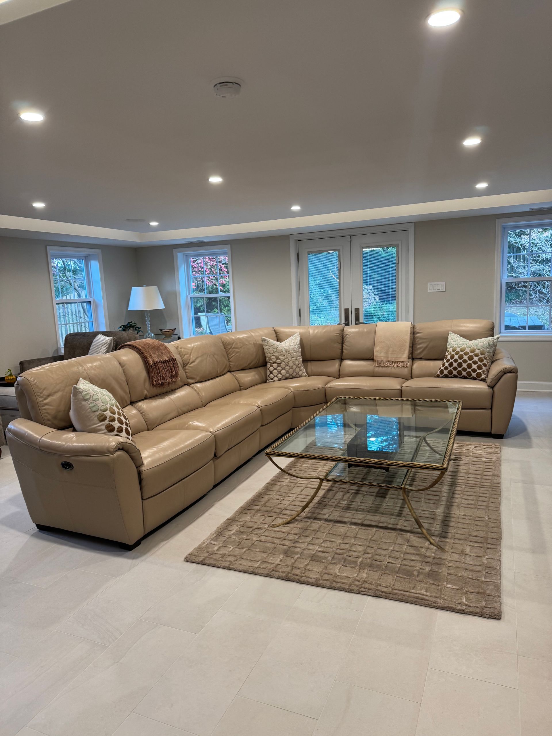 A living room with a large sectional couch and a glass coffee table.