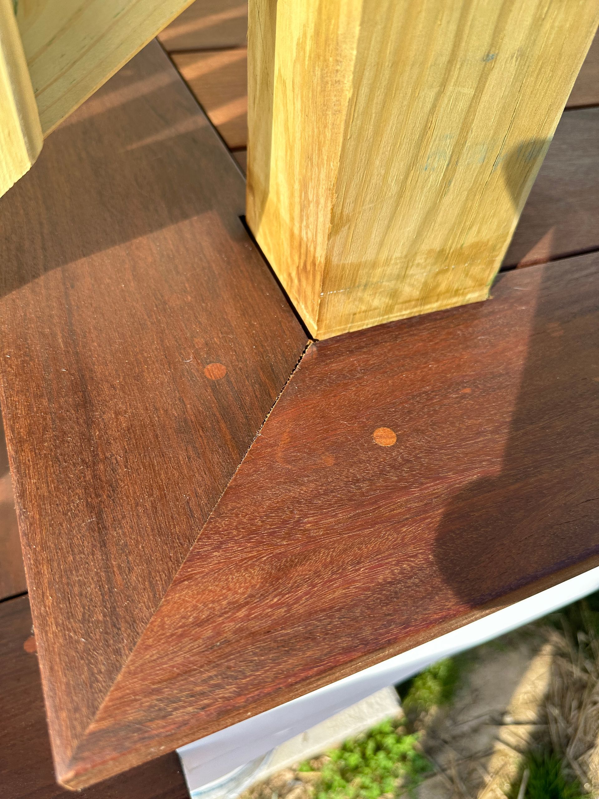 A close up of a wooden deck featuring mechanical dowel joints with a wooden railing.