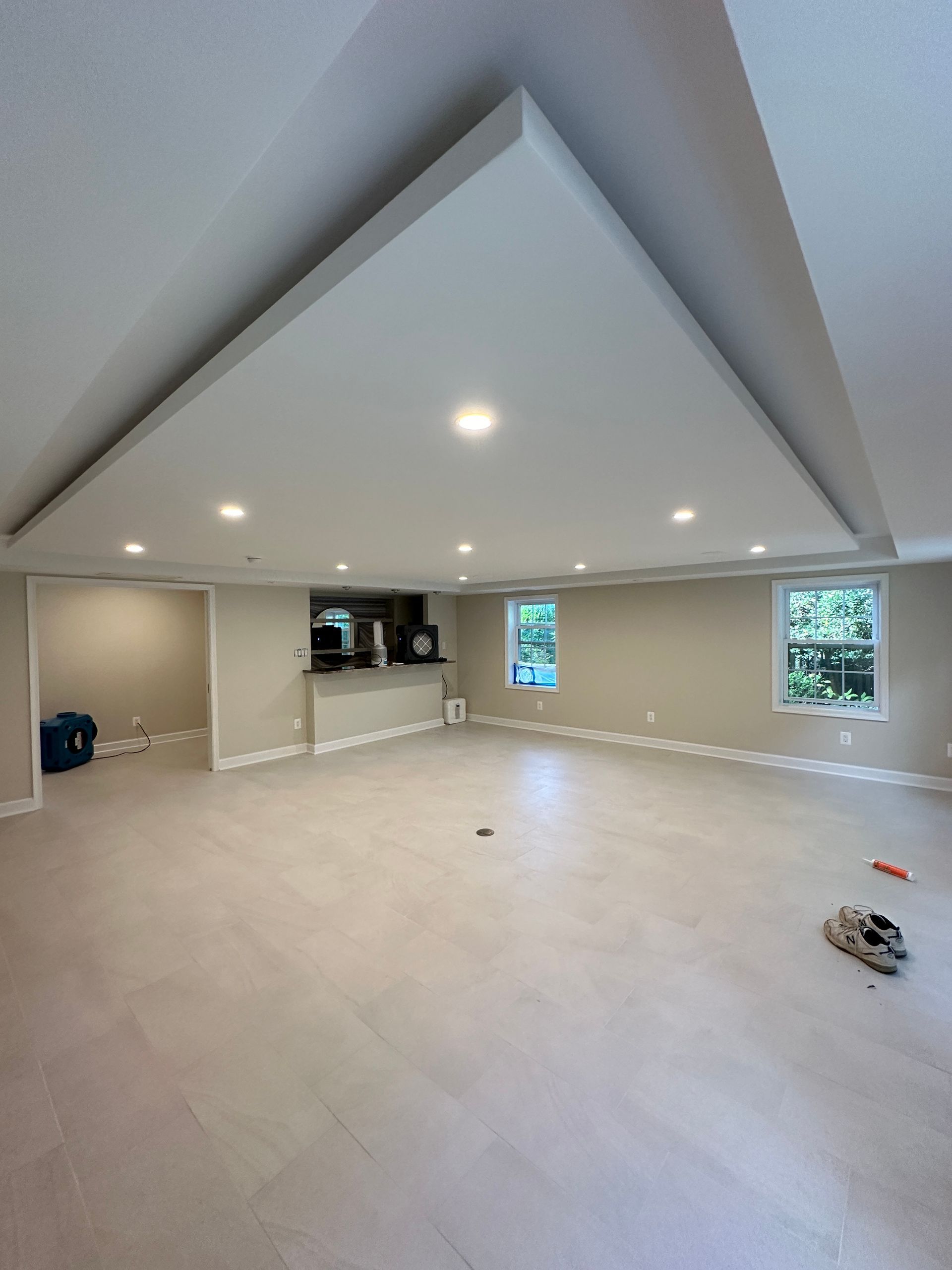 A large empty room with a tiled floor and a false white ceiling
