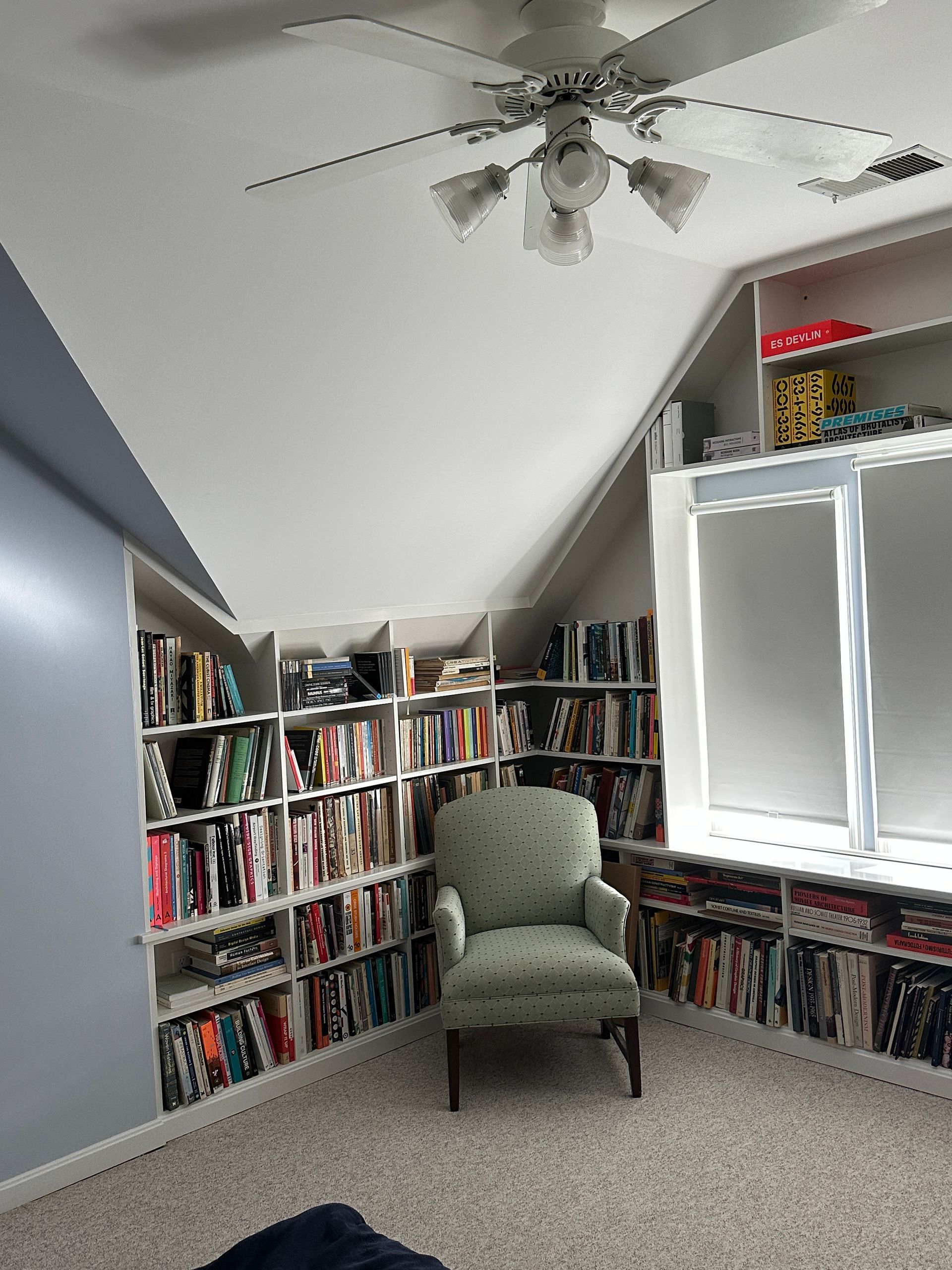 A library with a chair and a ceiling fan